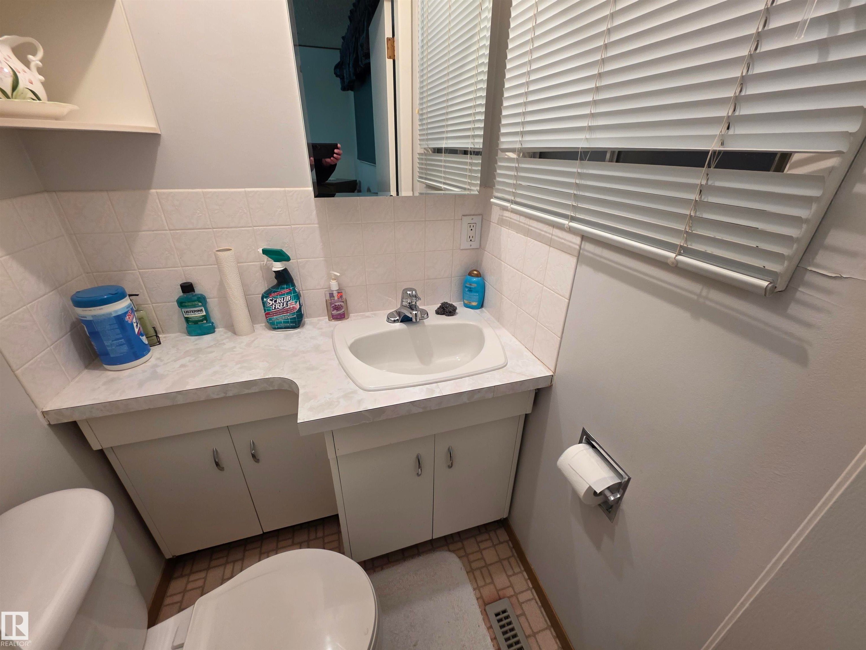Half bath with vanity and tasteful backsplash - 4400 45 Avenue, Stony Plain, AB - Indoor Photo Showing Bathroom