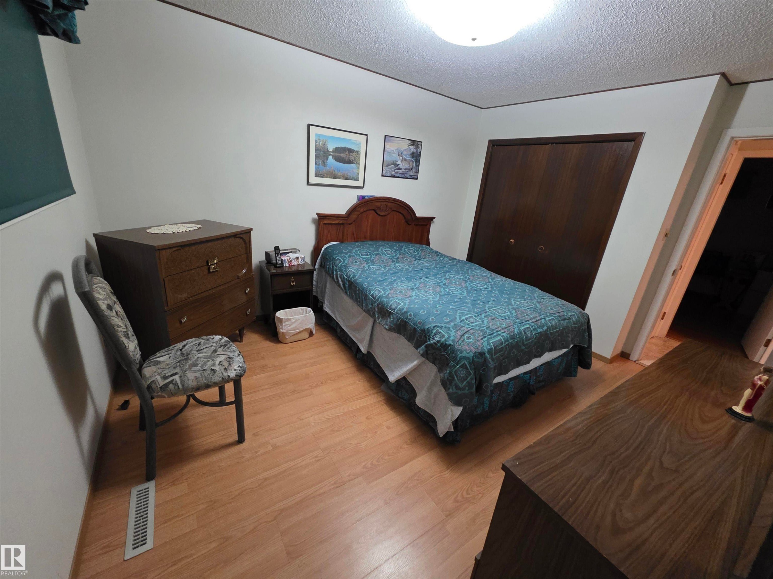 Bedroom with a closet, light wood-style flooring, and a textured ceiling - 4400 45 Avenue, Stony Plain, AB - Indoor Photo Showing Bedroom