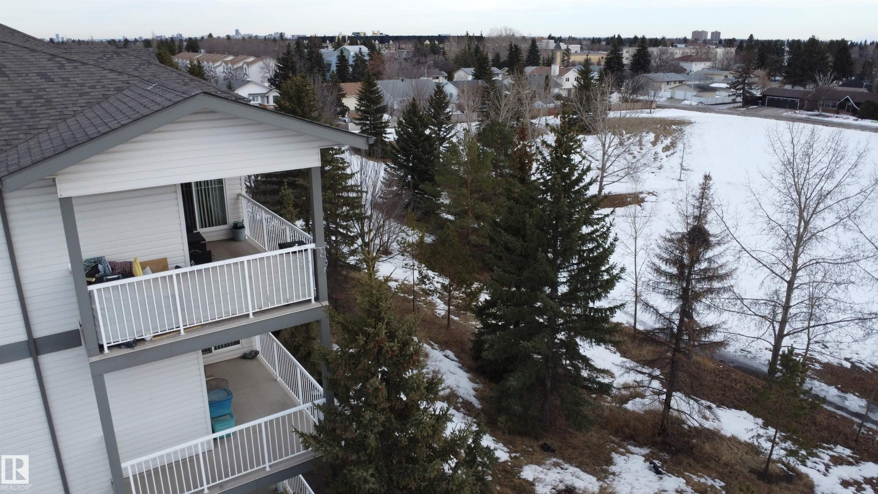 View of snowy exterior featuring a balcony, a residential view, and a shingled roof - 227 16807 100 Avenue, Edmonton, AB - Outdoor