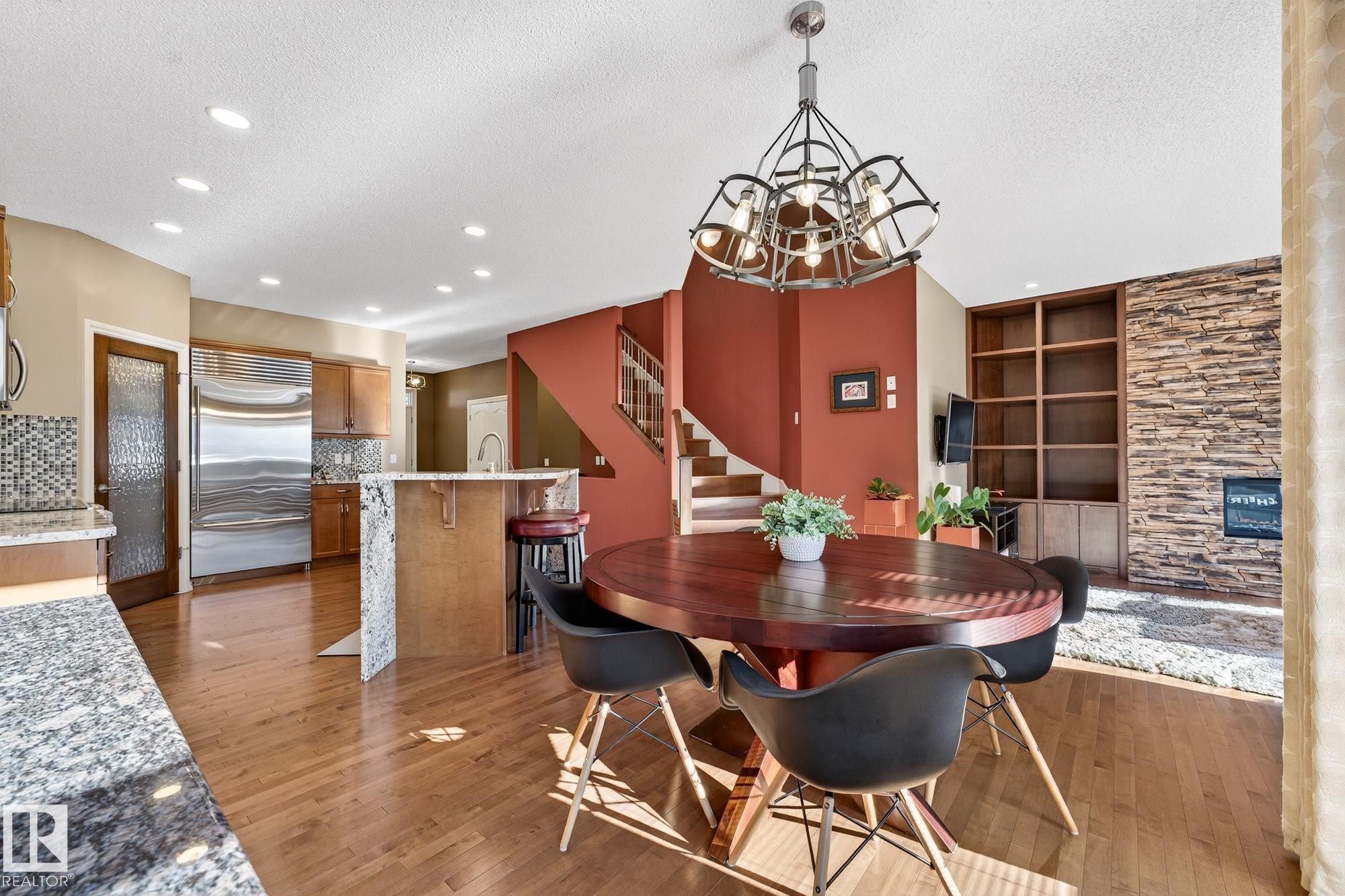 Dining area featuring suspended lighting, built in shelves, light wood-type flooring, and a textured ceiling - 2036 Hilliard Place, Edmonton, AB - Indoor Photo Showing Dining Room