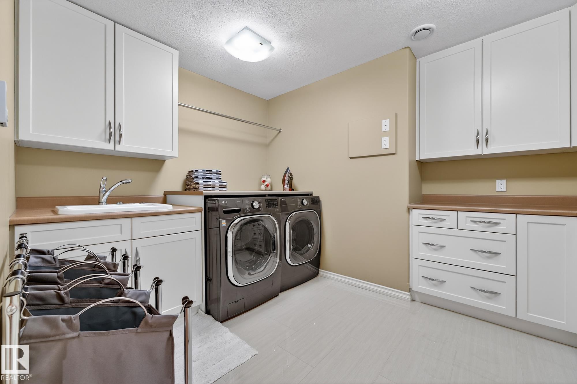 Laundry area with a textured ceiling, cabinet space, and washer and dryer - 2036 Hilliard Place, Edmonton, AB - Indoor Photo Showing Laundry Room