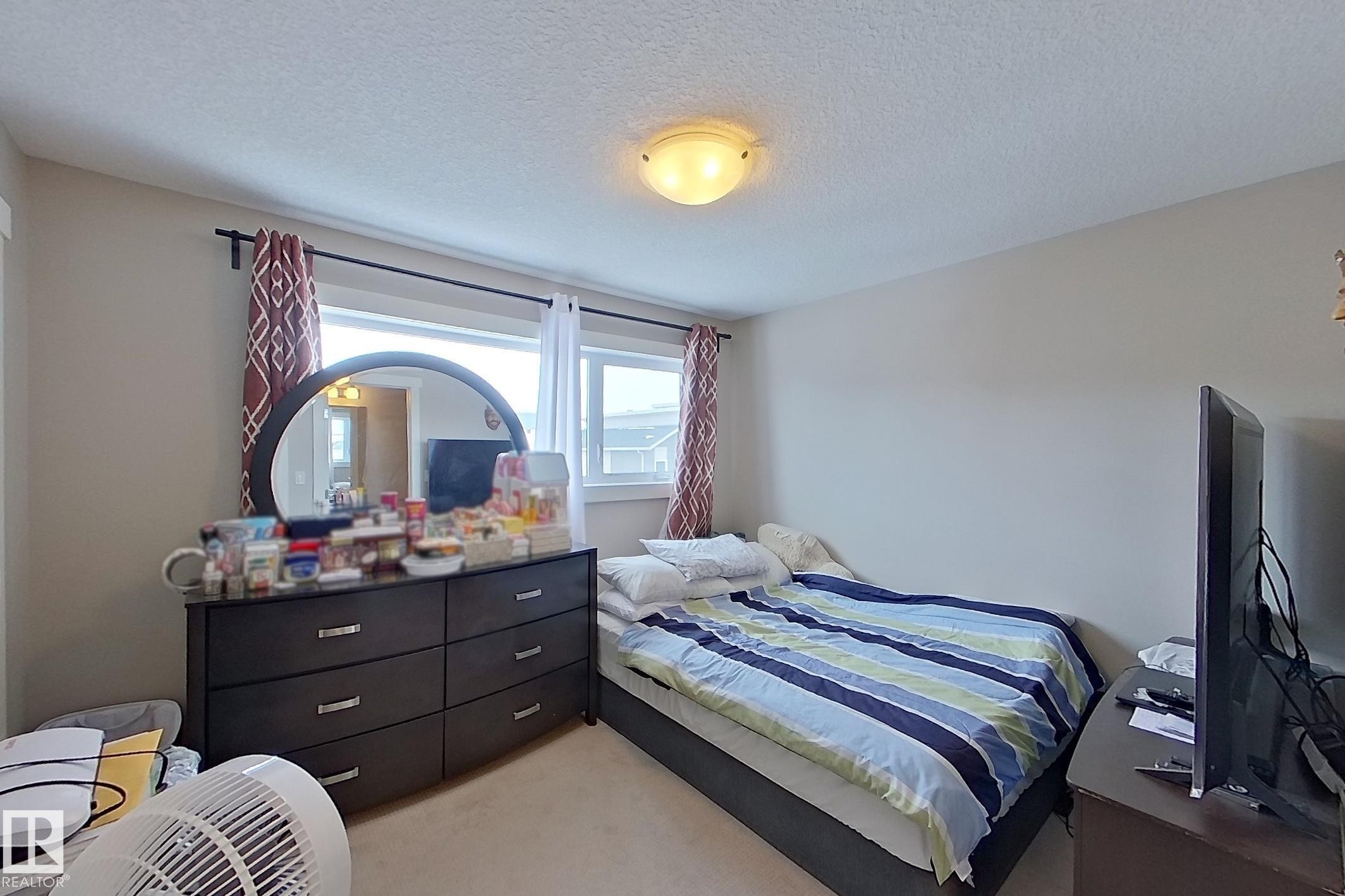 Bedroom with light carpet and a textured ceiling - 295 401 Southfork Drive, Leduc, AB - Indoor Photo Showing Bedroom