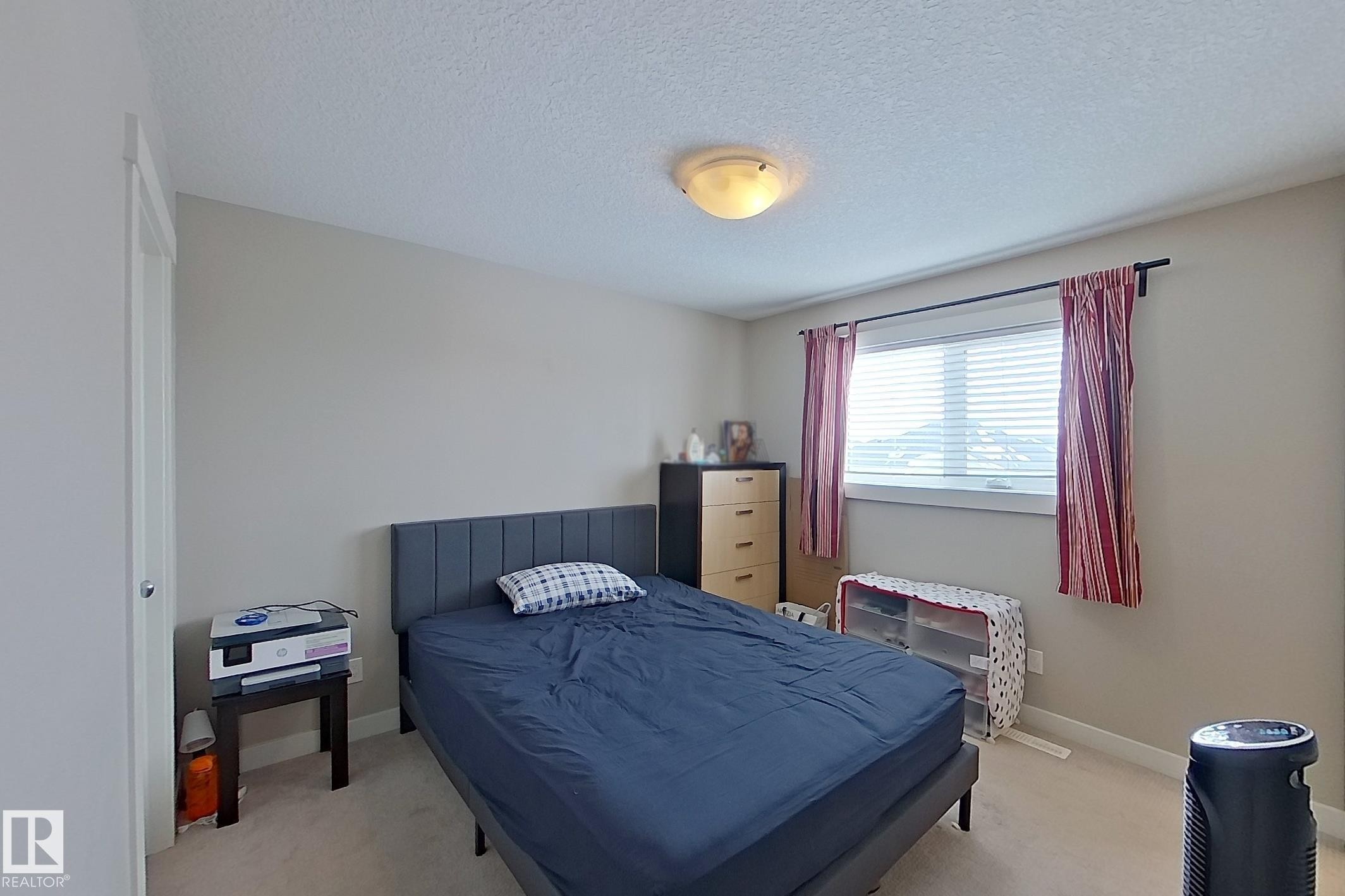 Bedroom with light carpet and a textured ceiling - 295 401 Southfork Drive, Leduc, AB - Indoor Photo Showing Bedroom