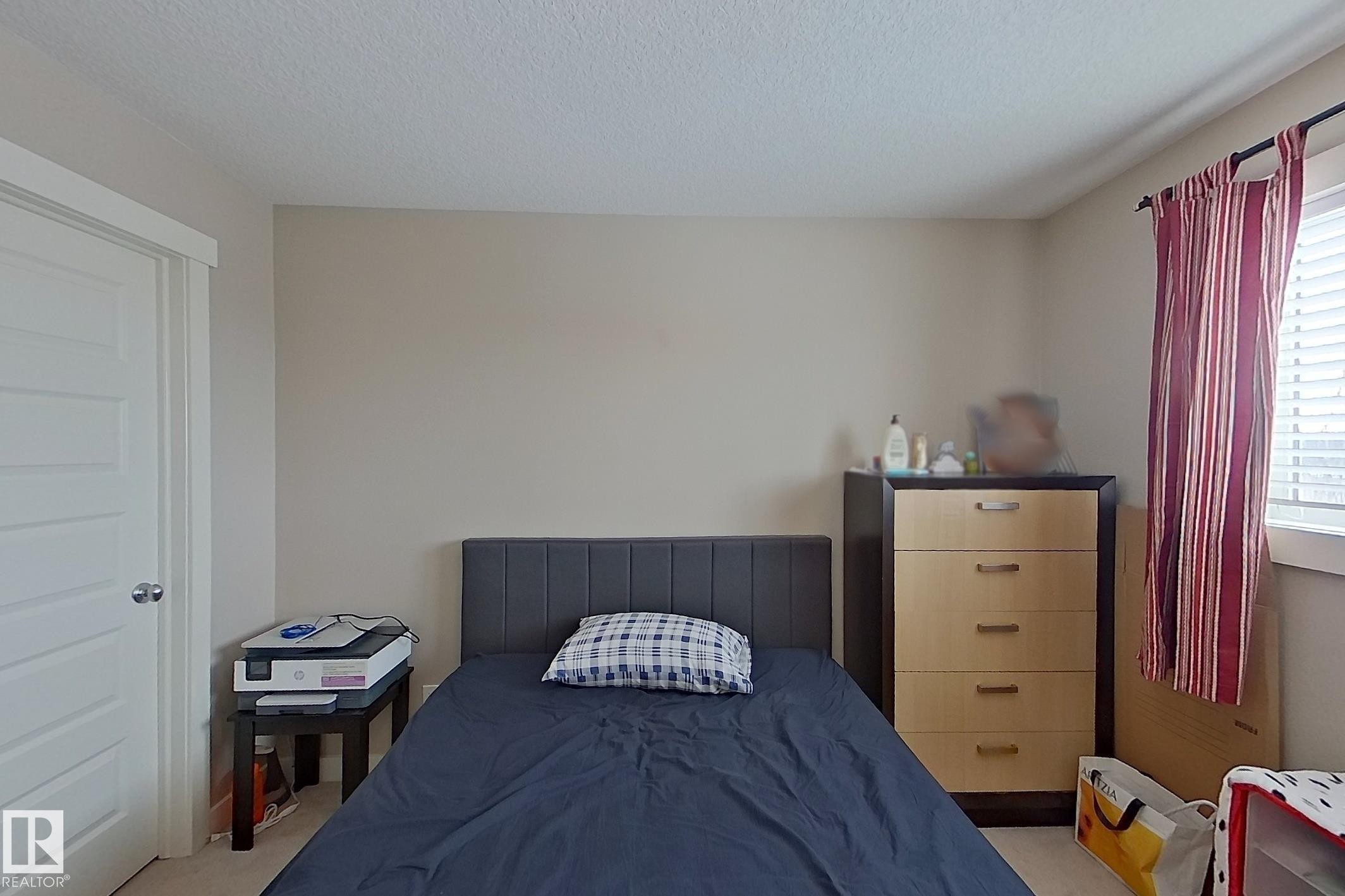 Bedroom with light colored carpet and a textured ceiling - 295 401 Southfork Drive, Leduc, AB - Indoor Photo Showing Bedroom