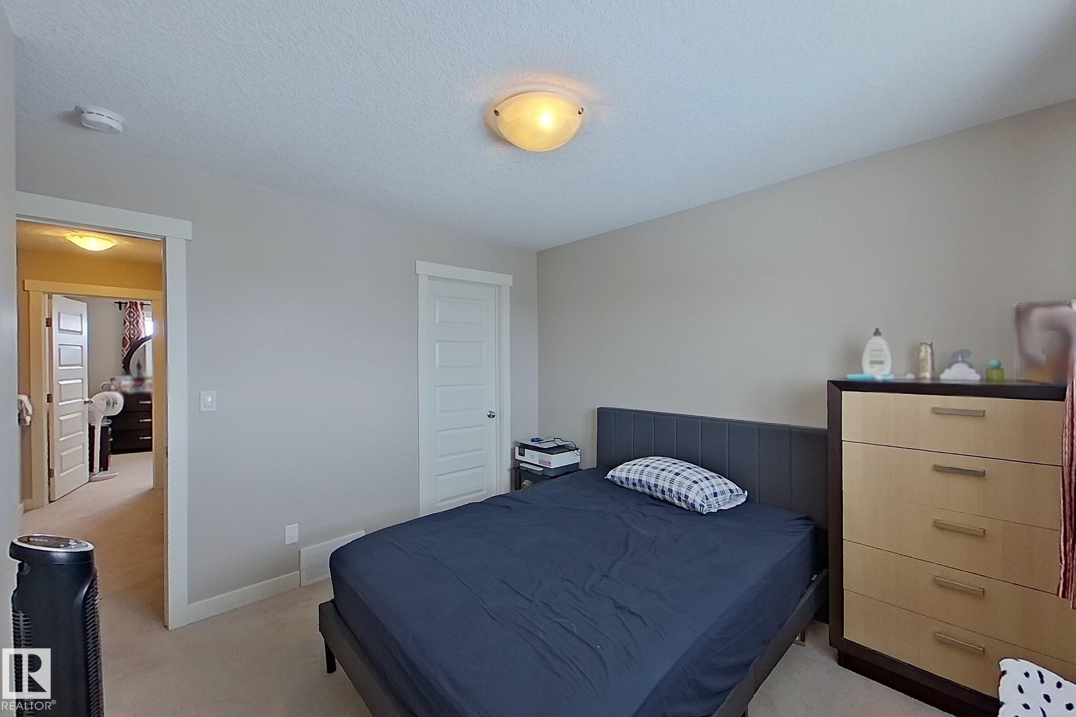 Bedroom with light carpet and a textured ceiling - 295 401 Southfork Drive, Leduc, AB - Indoor Photo Showing Bedroom