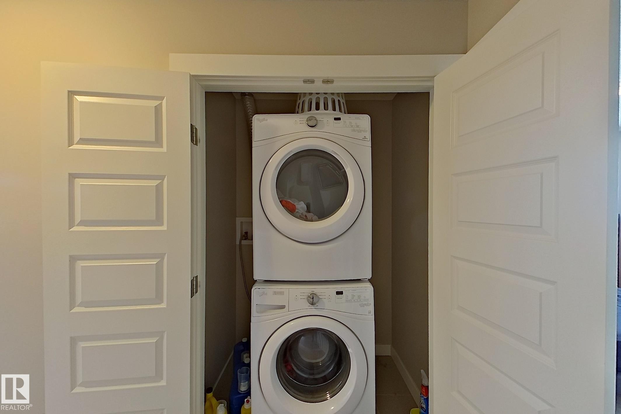 Laundry area featuring stacked washer and clothes dryer and baseboards - 295 401 Southfork Drive, Leduc, AB - Indoor Photo Showing Laundry Room
