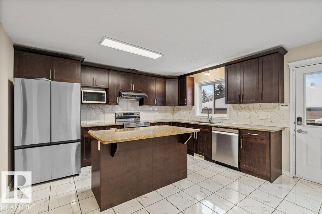 Kitchen with dark brown cabinetry, appliances with stainless steel finishes, and light marble finish flooring - 10639 70 Avenue, Edmonton, AB - Indoor Photo Showing Kitchen With Upgraded Kitchen