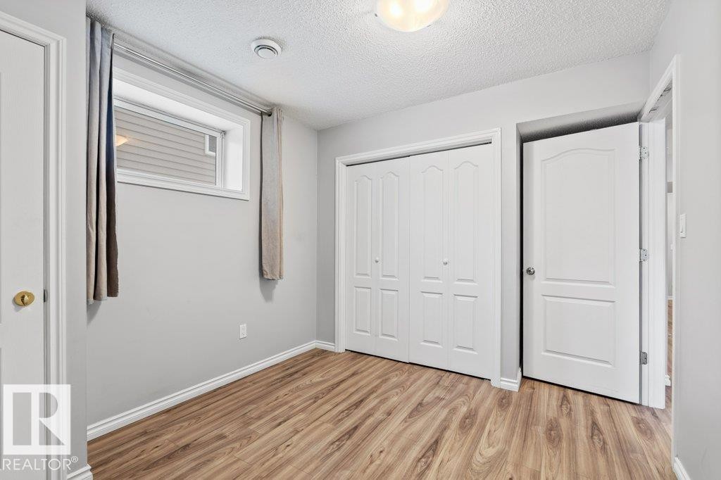 Unfurnished bedroom featuring a textured ceiling, a closet, and light wood-style flooring - 10639 70 Avenue, Edmonton, AB - Indoor Photo Showing Other Room