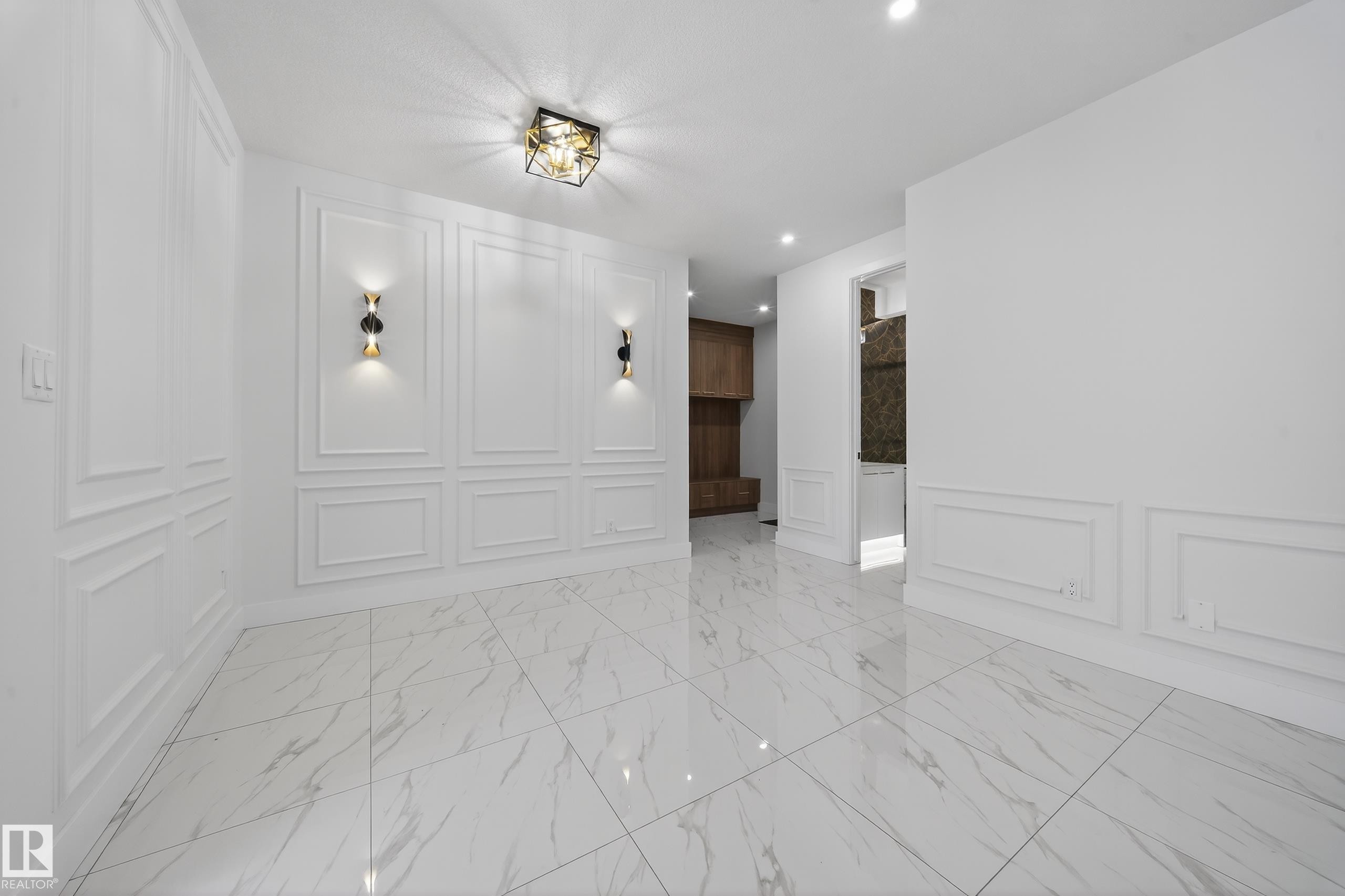 Unfurnished room with a decorative wall, light marble finish flooring, recessed lighting, and wainscoting - 4006 40 Street, Beaumont, AB - Indoor Photo Showing Other Room