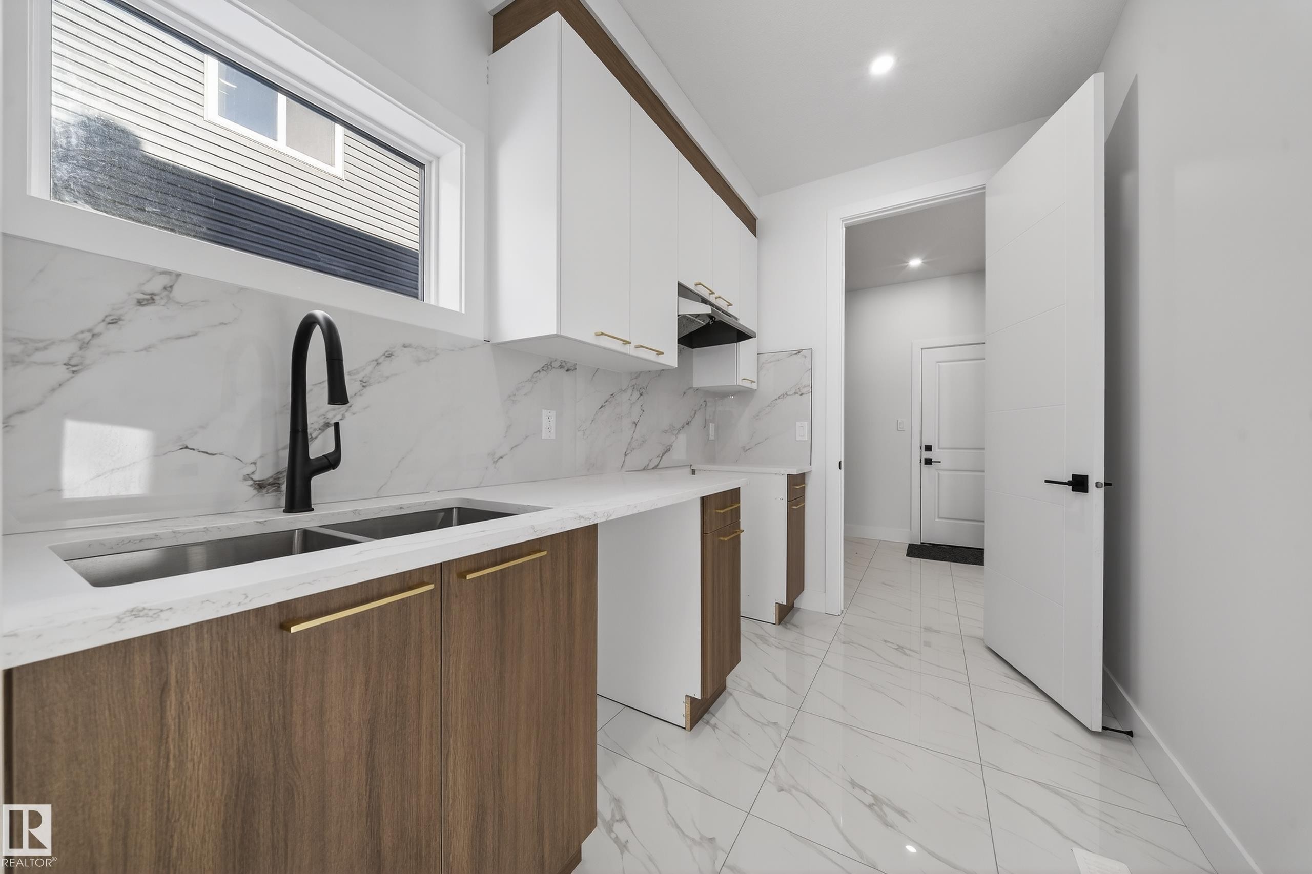 Dual tone kitchen featuring light marble finish floors, modern cabinets, two tone cabinetry, light stone countertops, and decorative backsplash - 4006 40 Street, Beaumont, AB - Indoor Photo Showing Kitchen With Double Sink