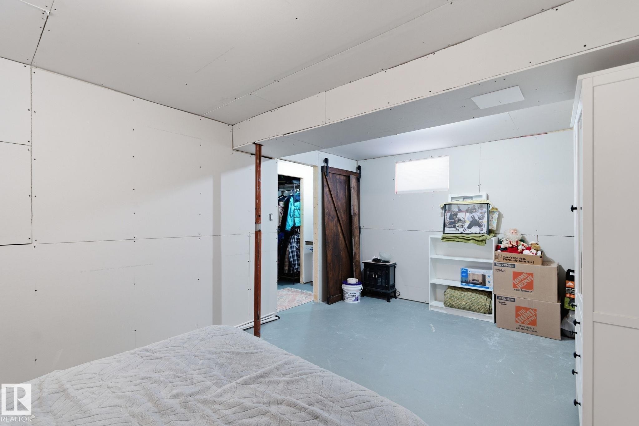 basement with finished concrete floors and a barn door - 4919 50 Avenue, Bon Accord, AB - Indoor