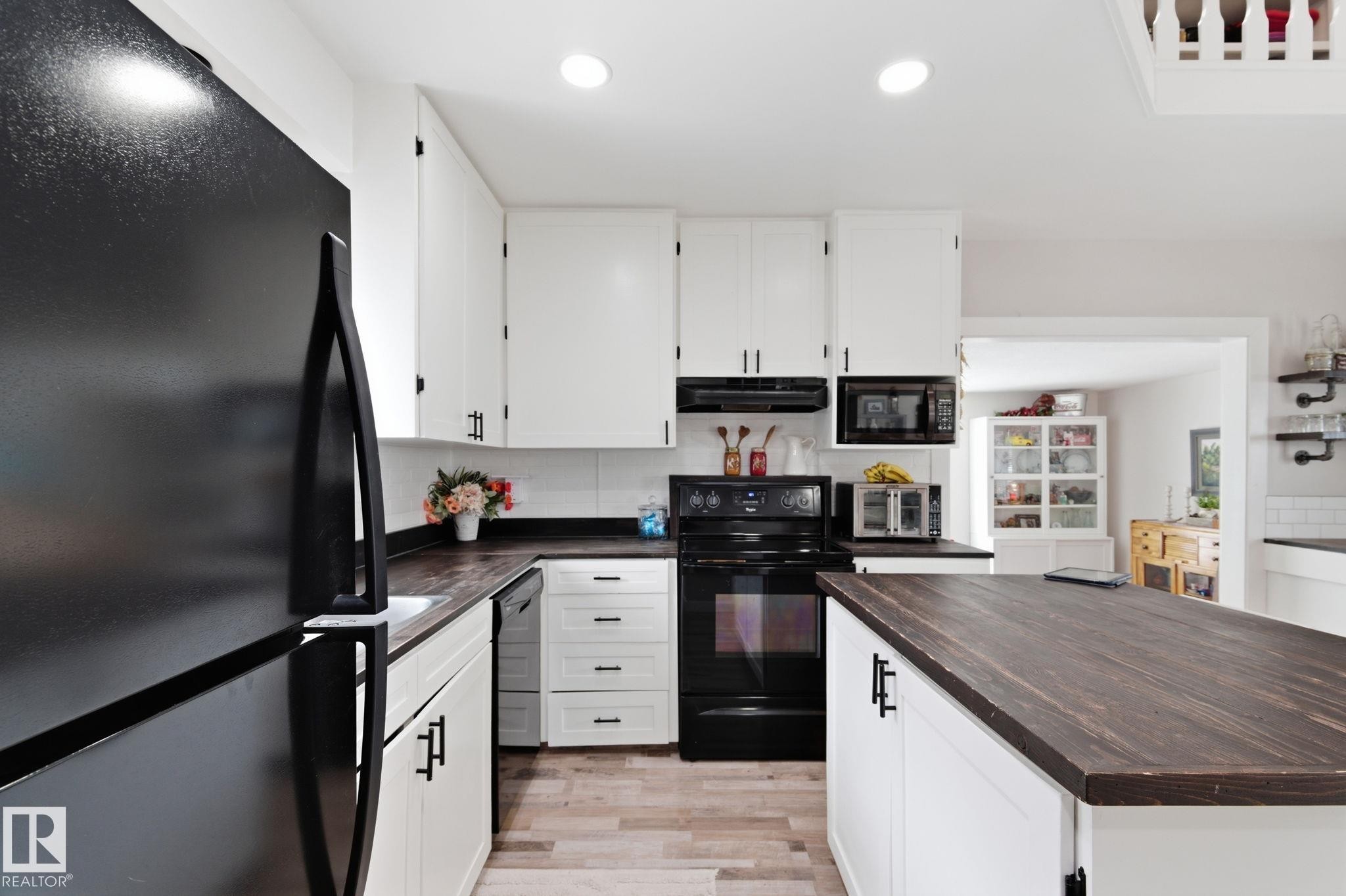 Kitchen with black appliances, white cabinetry, light wood-style floors, butcher block countertops, and recessed lighting - 4919 50 Avenue, Bon Accord, AB - Indoor Photo Showing Kitchen