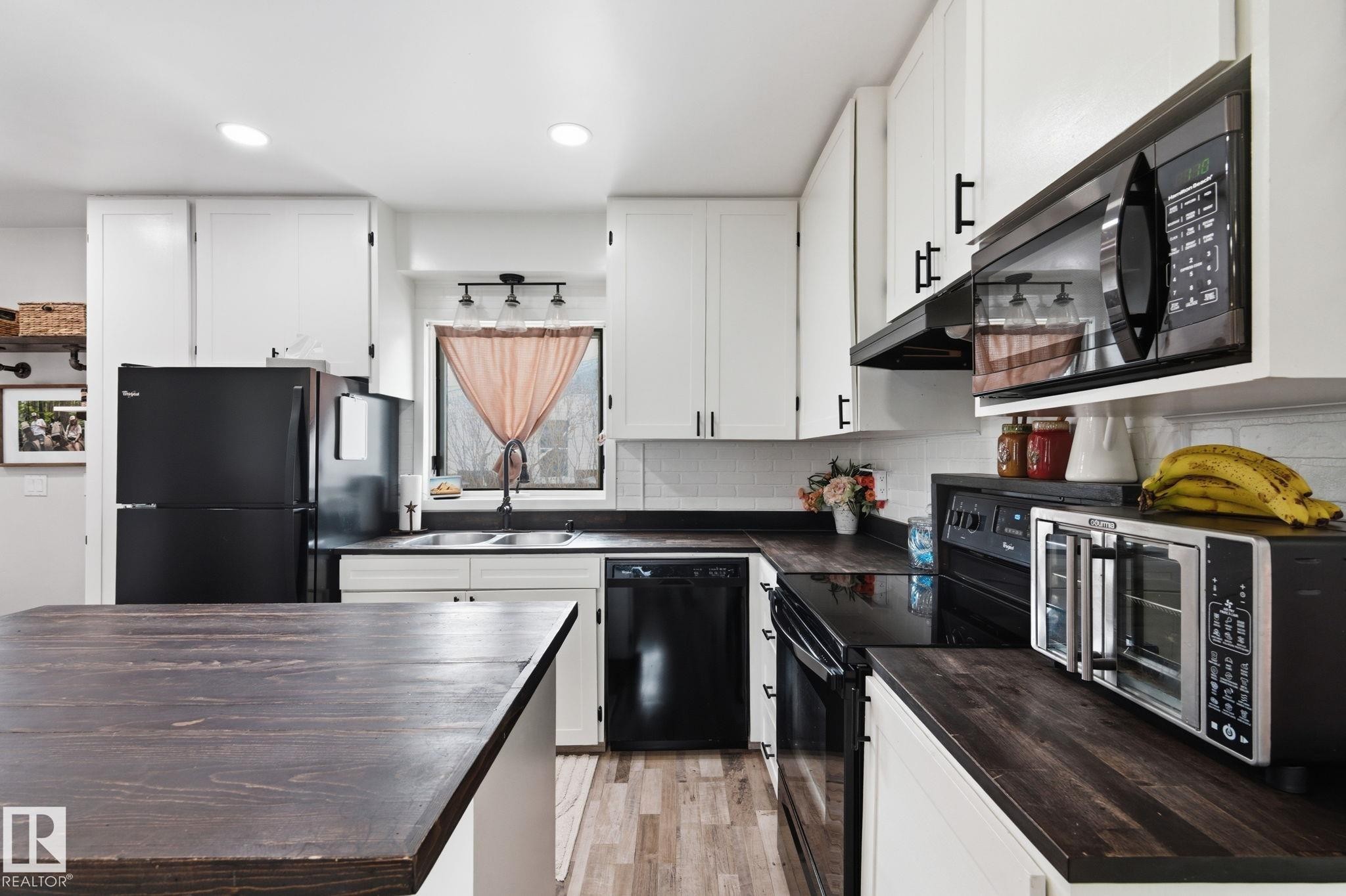 Kitchen featuring black appliances, white cabinets, light wood-style floors, recessed lighting, and a kitchen island - 4919 50 Avenue, Bon Accord, AB - Indoor Photo Showing Kitchen