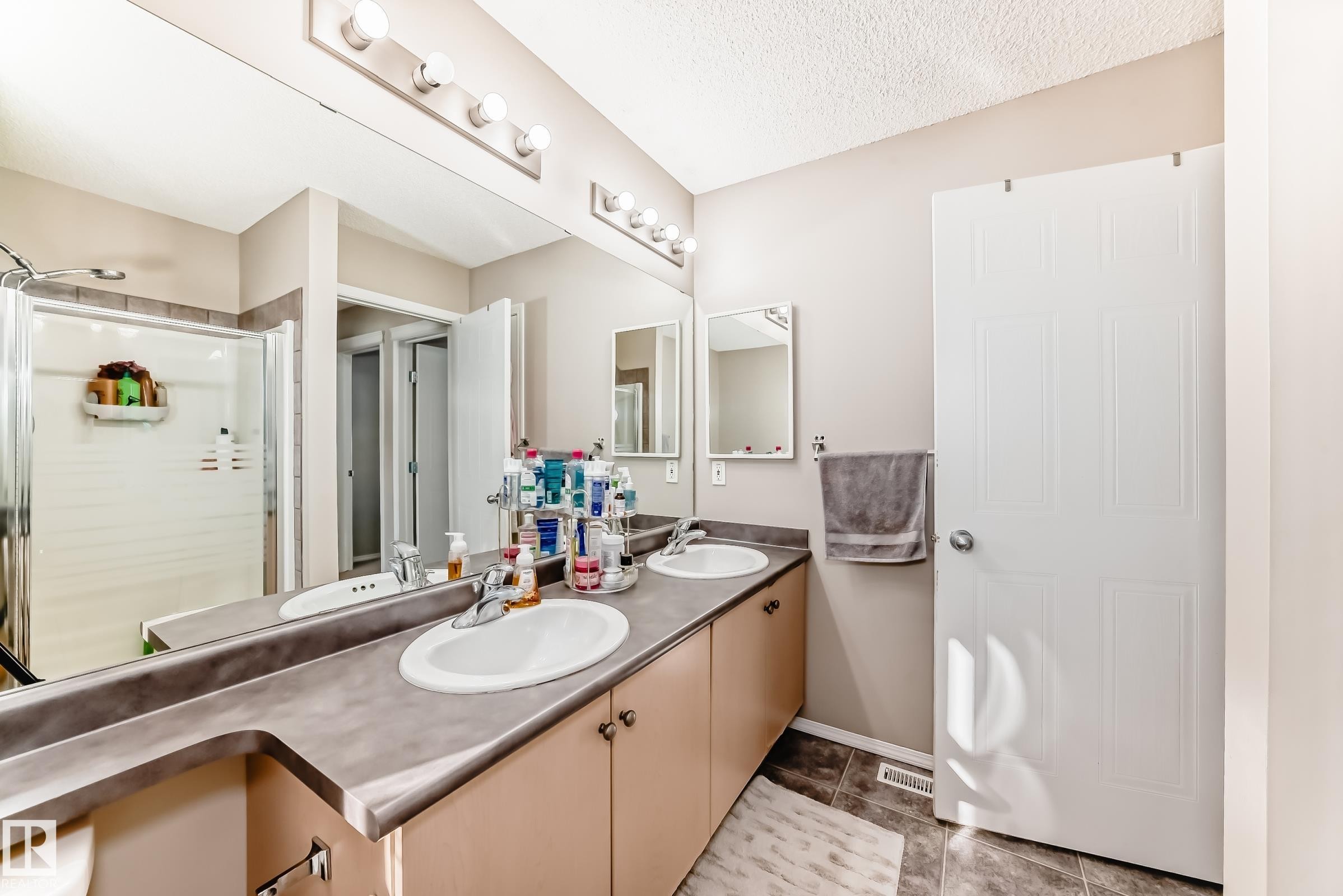 Full bathroom featuring double vanity, a stall shower, and a textured ceiling - 14043 151 Avenue, Edmonton, AB - Indoor Photo Showing Bathroom