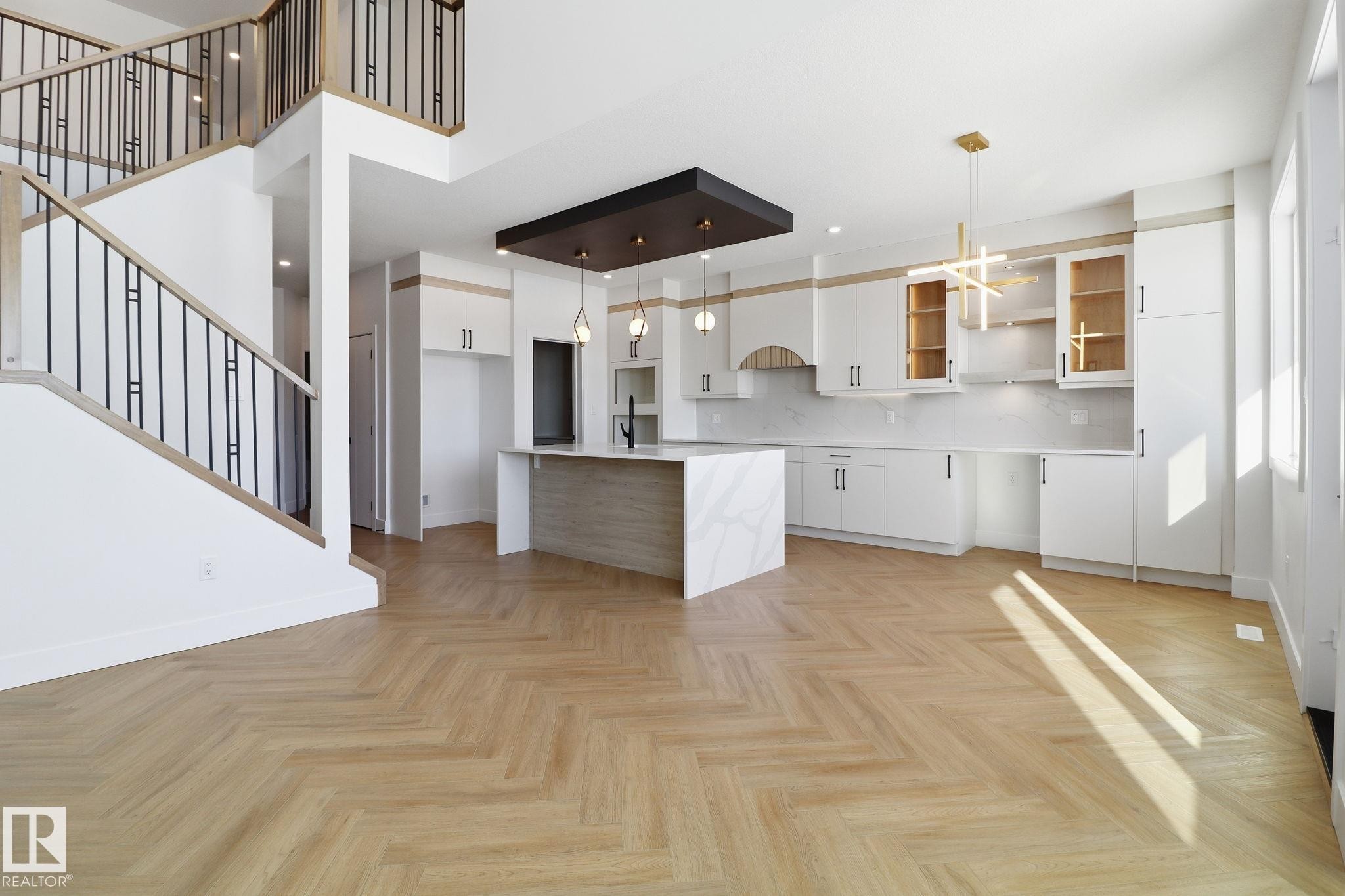 Kitchen with hanging light fixtures, parquet floors, modern cabinets, a breakfast bar, and two tone color scheme - 90 Eldridge Point(E), St. Albert, AB - Indoor Photo Showing Kitchen
