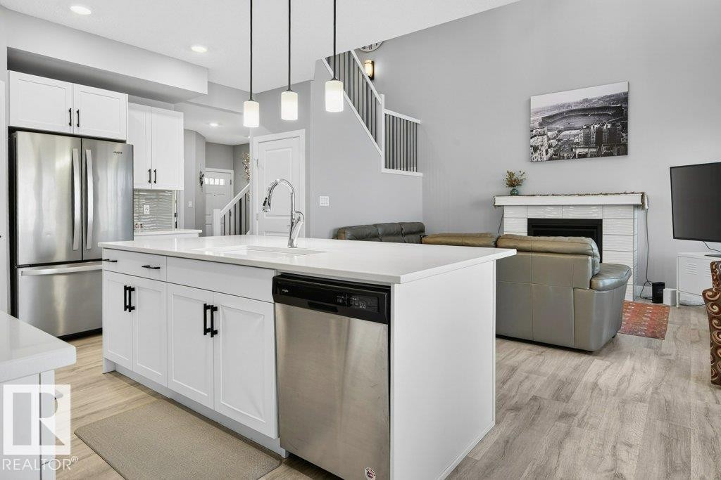 View from kitchen nook/dining area into kitchen and open-to-below great room. - 1909 Davidson Wynd, Edmonton, AB - Indoor Photo Showing Kitchen With Fireplace With Upgraded Kitchen
