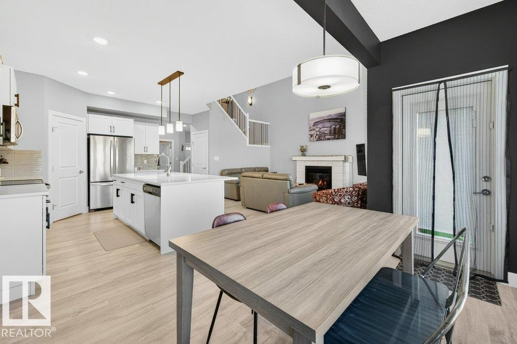 View from dining area into the kitchen, the expansive open-to-below great room, and grand open staircase up to the second level. - 1909 Davidson Wynd, Edmonton, AB - Indoor