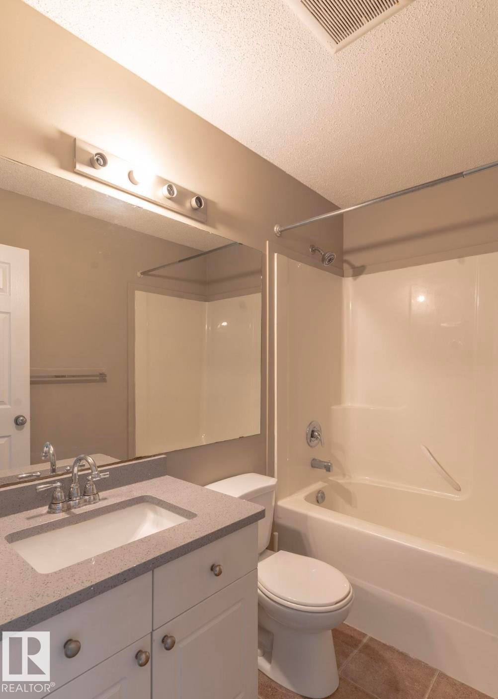 Full bath with vanity, a textured ceiling, tub / shower combination, and tile patterned flooring - 13616 82 Street Nw, Edmonton, AB - Indoor Photo Showing Bathroom