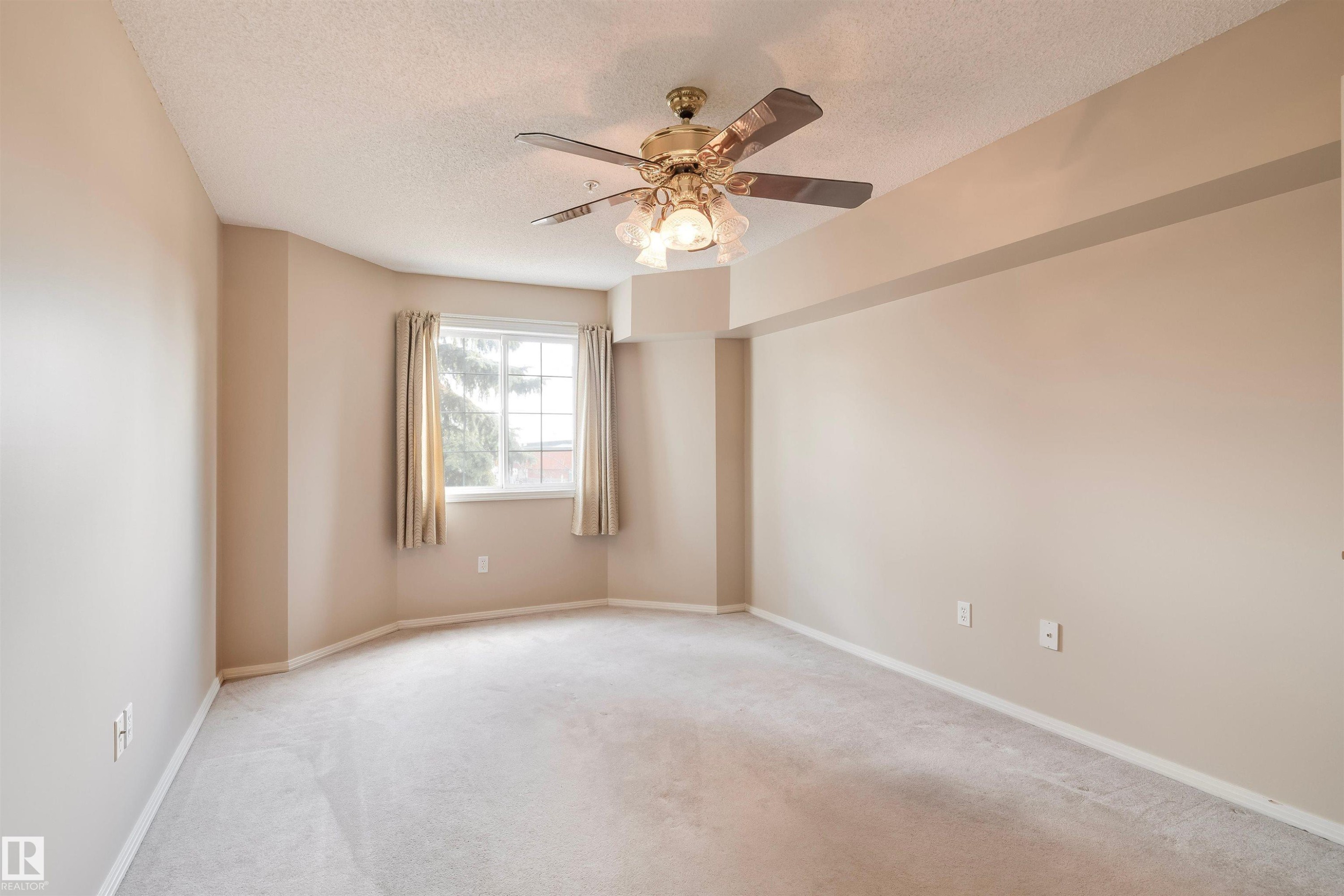 Spare room featuring a textured ceiling, carpet, and ceiling fan - 209 17150 94A Avenue, Edmonton, AB - Indoor Photo Showing Other Room