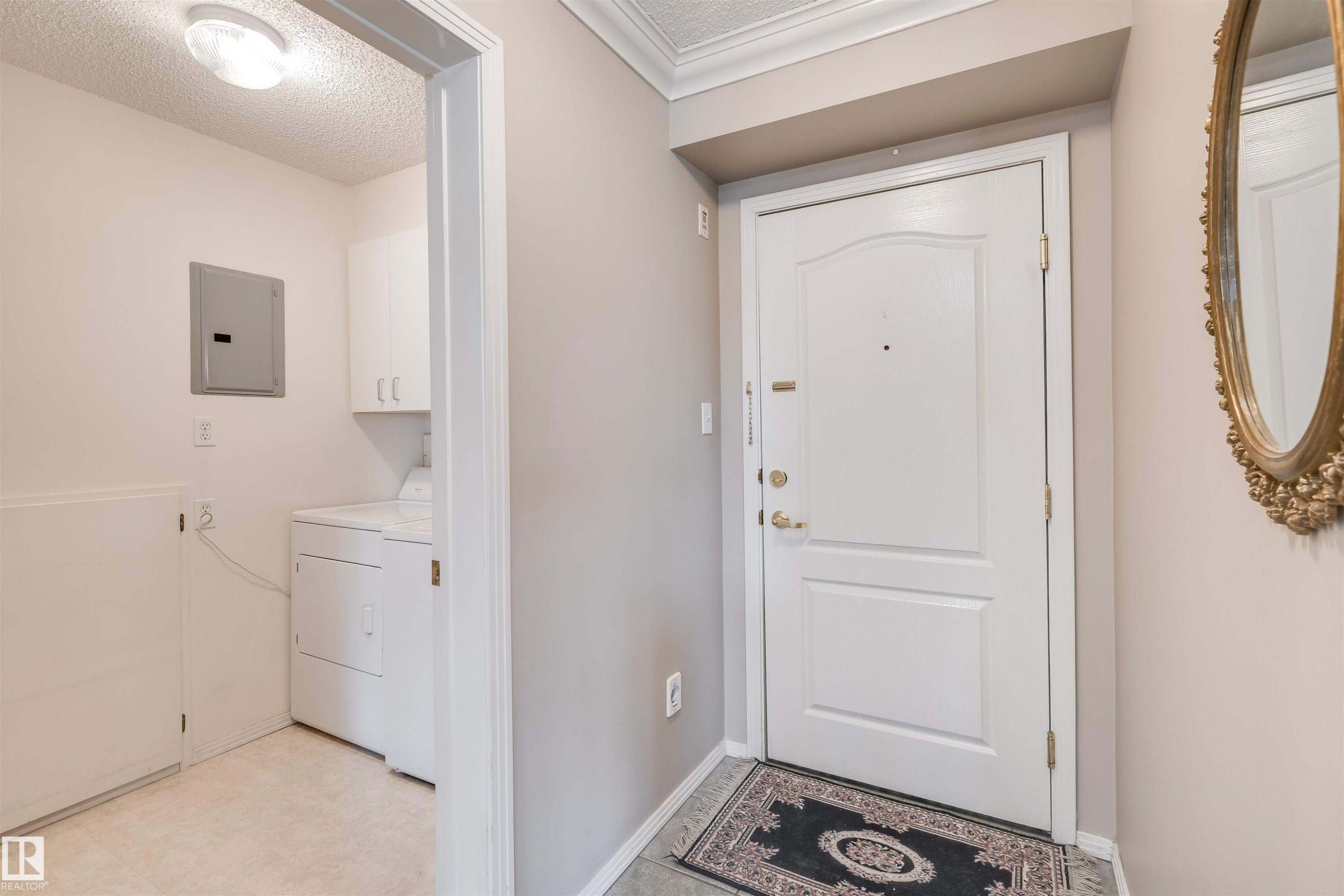 Entryway featuring a textured ceiling, electric panel, tile patterned floors, and independent washer and dryer - 209 17150 94A Avenue, Edmonton, AB - Indoor Photo Showing Laundry Room