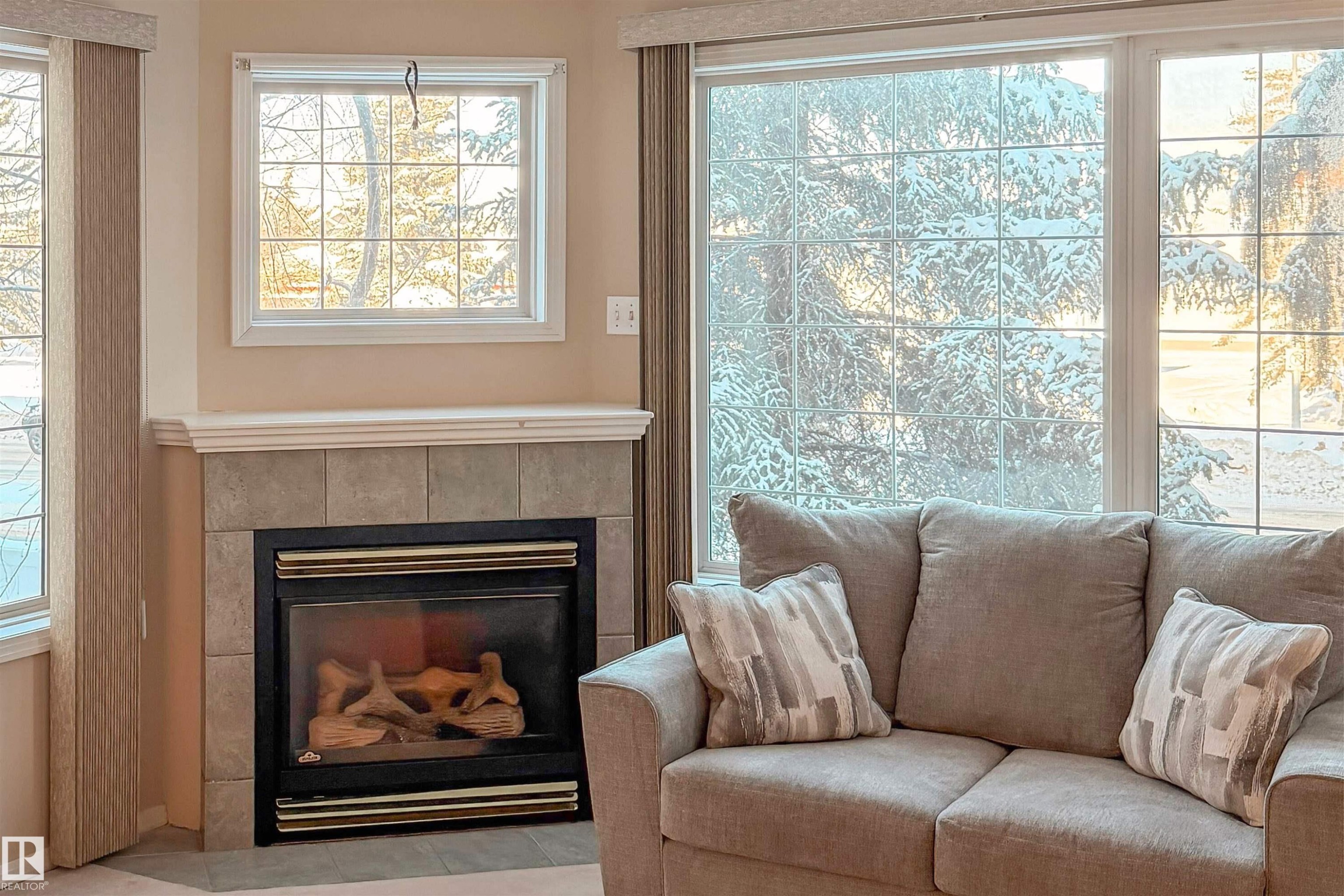 Living area featuring a tiled fireplace and plenty of natural light - 209 17150 94A Avenue, Edmonton, AB - Indoor Photo Showing Living Room With Fireplace