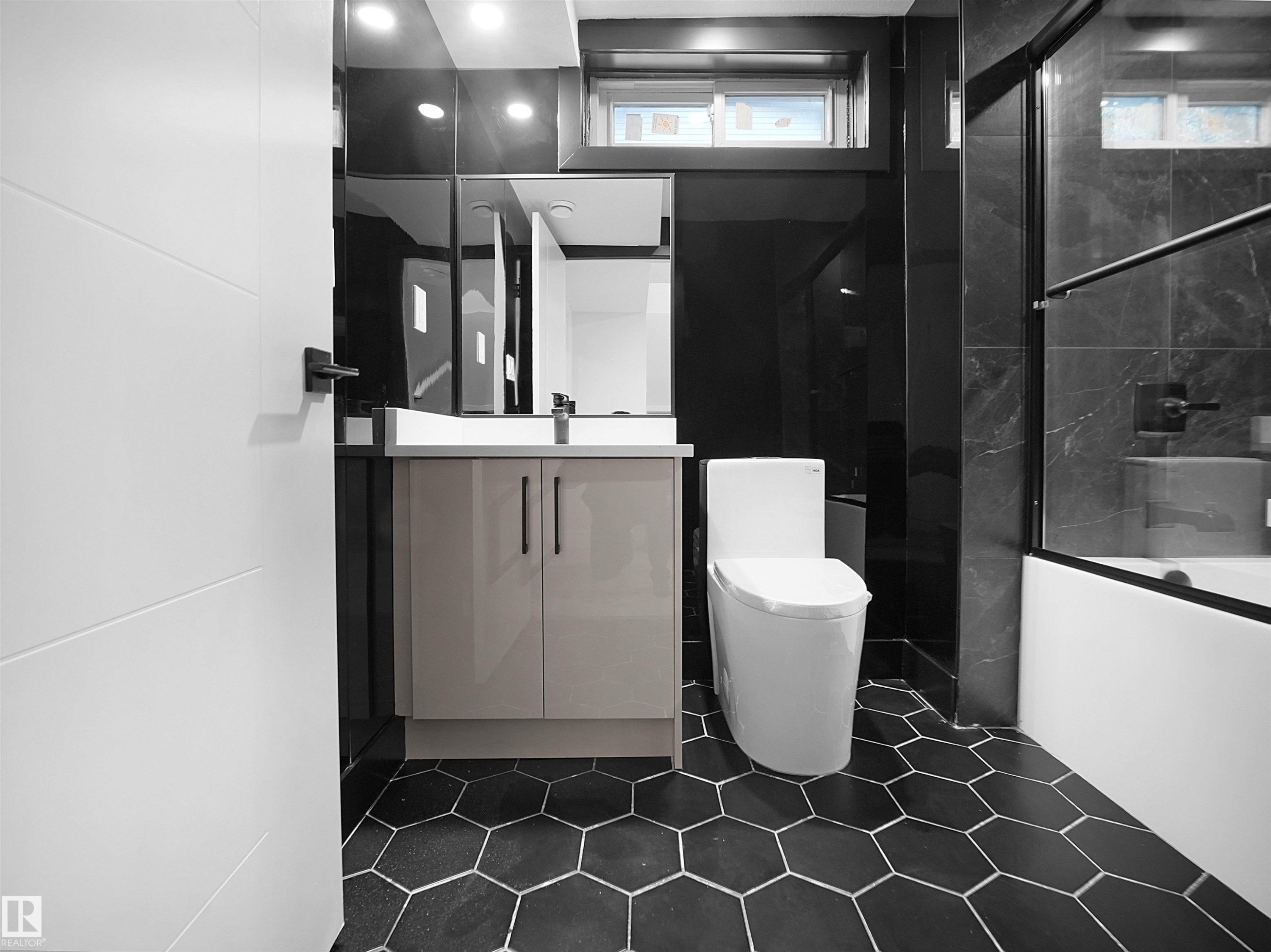 Full bath featuring vanity, combined bath / shower with glass door, dark tile patterned floors, and tile walls - 9409 173 Street, Edmonton, AB - Indoor Photo Showing Other Room