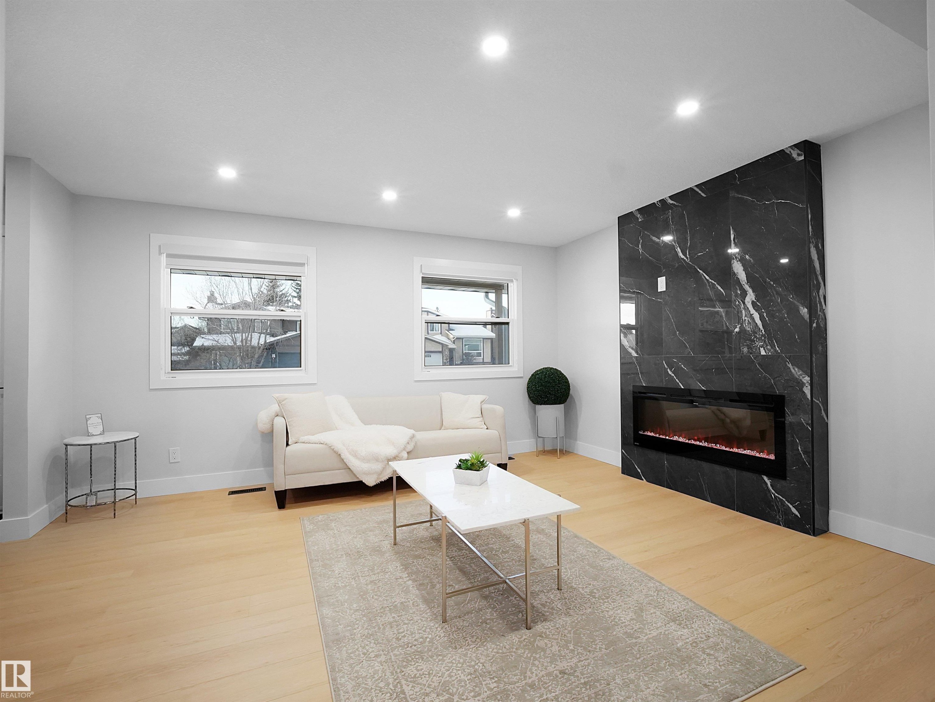 Living area featuring light wood finished floors, recessed lighting, and a premium fireplace - 9409 173 Street, Edmonton, AB - Indoor Photo Showing Living Room With Fireplace