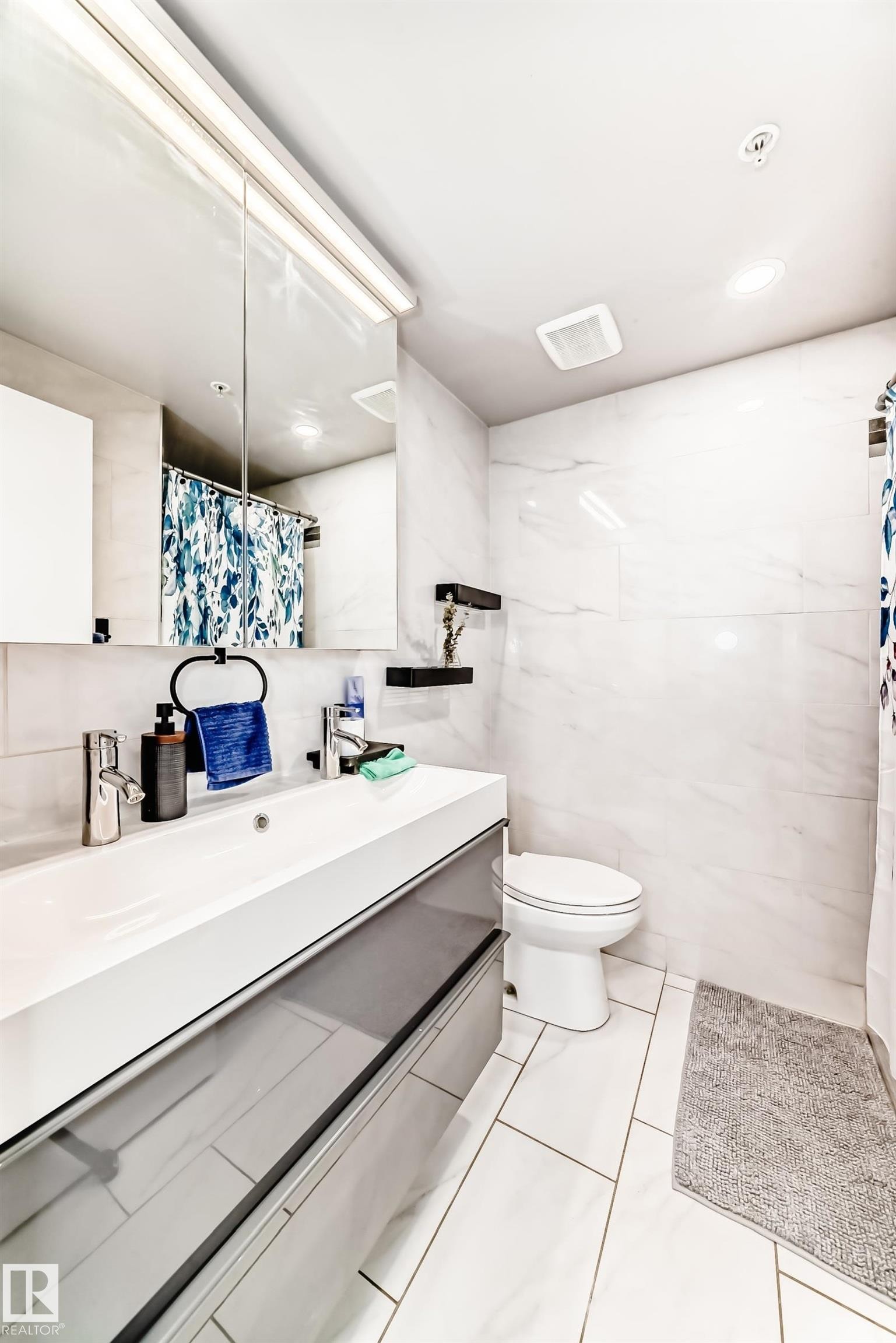 Bathroom with curtained shower, vanity, tile walls, and light tile patterned floors - 2004 10136 104 Street, Edmonton, AB - Indoor Photo Showing Bathroom