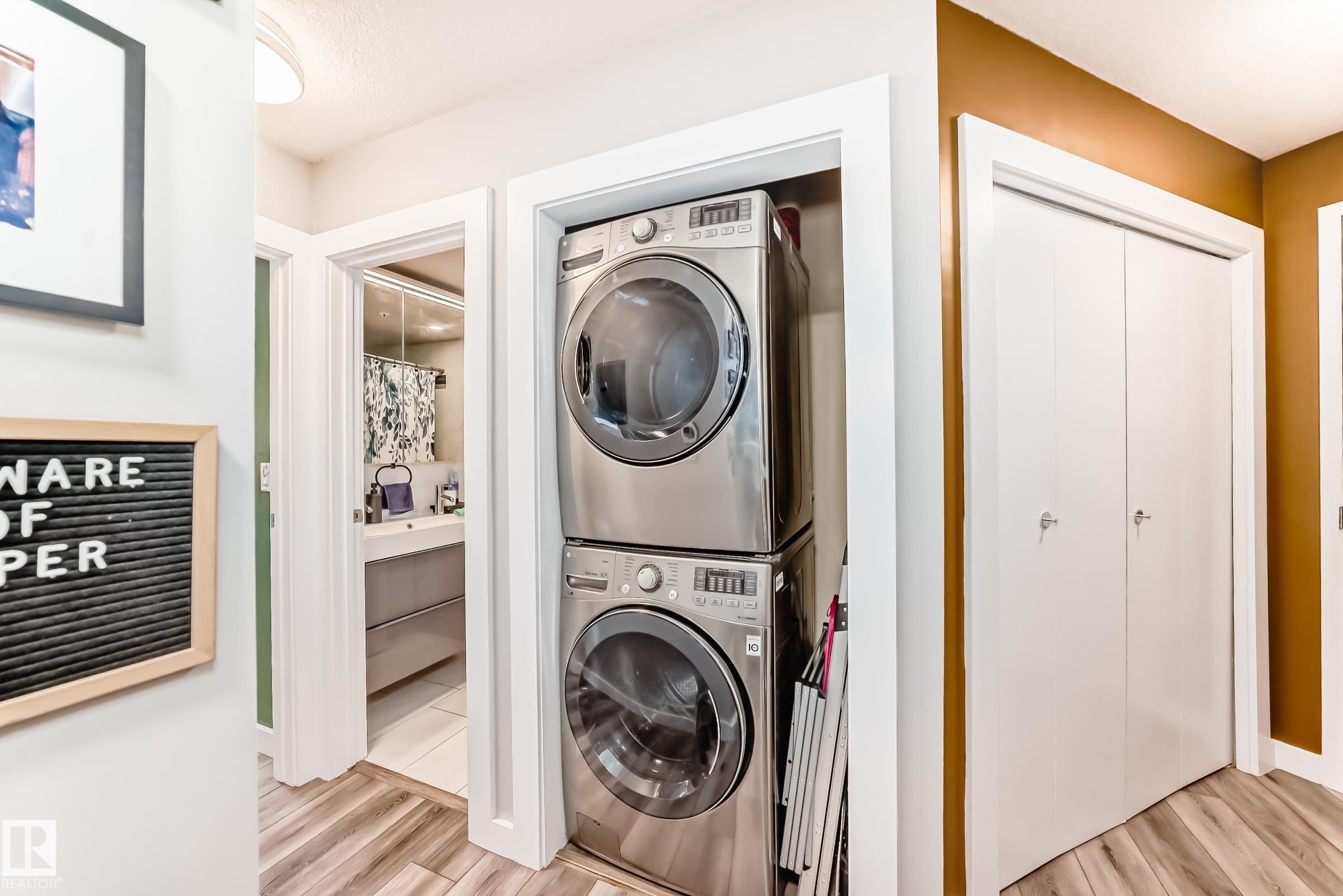 Laundry area featuring stacked washer / drying machine and light wood-type flooring - 2004 10136 104 Street, Edmonton, AB - Indoor Photo Showing Laundry Room