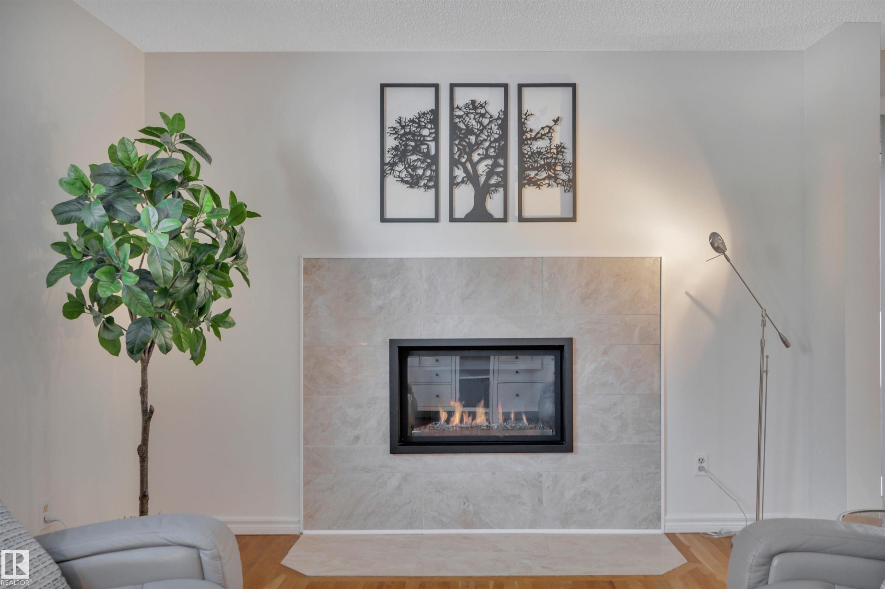 Living room with a tiled fireplace, wood finished floors, and a textured ceiling - 7075 32 Avenue, Edmonton, AB - Indoor Photo Showing Living Room With Fireplace