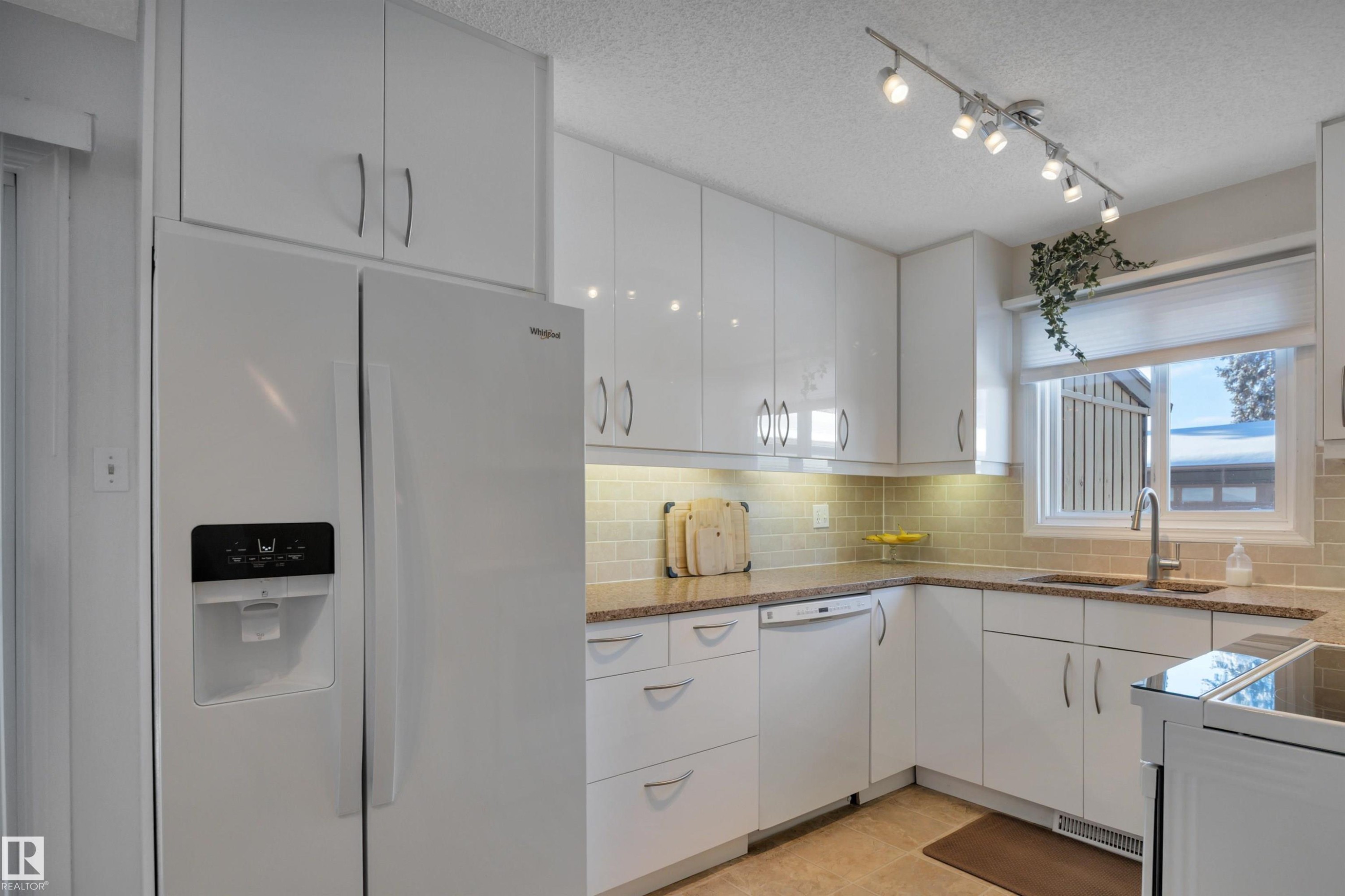 Kitchen featuring white appliances, white cabinetry, a textured ceiling, decorative backsplash, and light stone counters - 7075 32 Avenue, Edmonton, AB - Indoor Photo Showing Kitchen