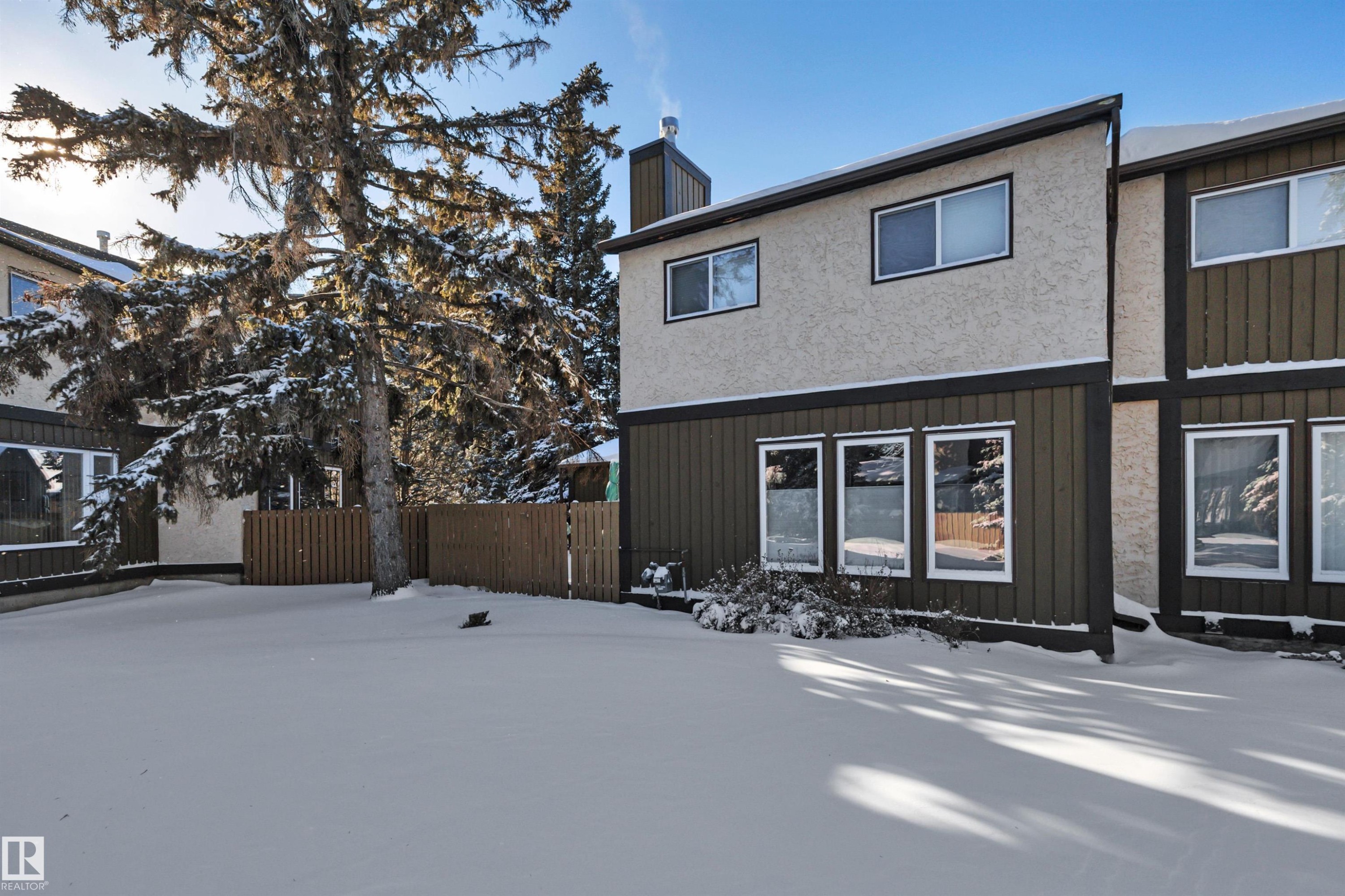 Snow covered rear of property featuring a chimney and board and batten siding - 7075 32 Avenue, Edmonton, AB - Outdoor