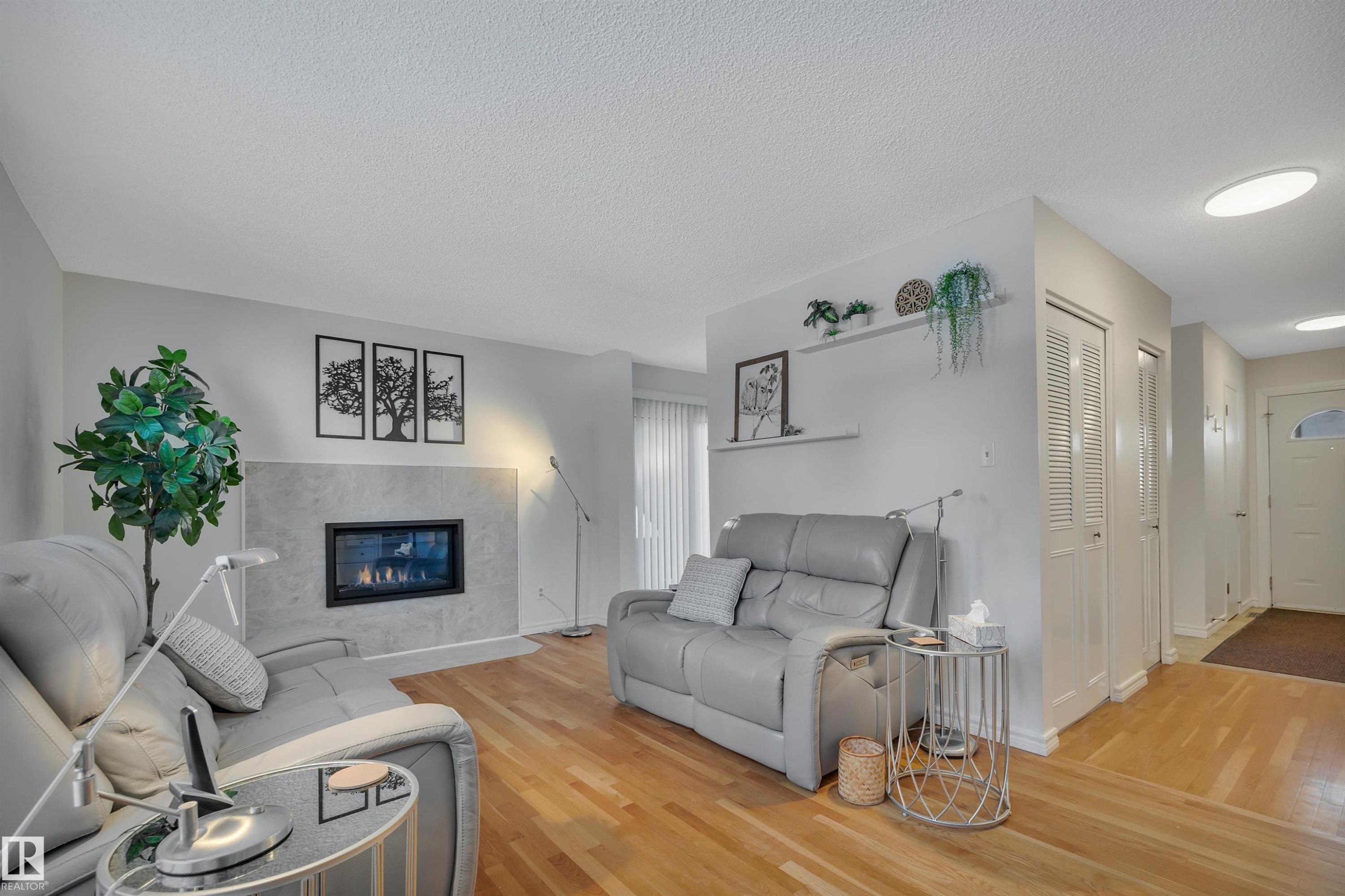 Living area with light wood-type flooring, a premium fireplace, and a textured ceiling - 7075 32 Avenue, Edmonton, AB - Indoor Photo Showing Living Room With Fireplace