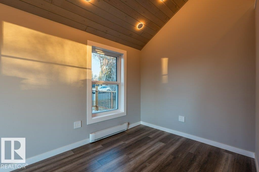 Unfurnished room with a baseboard heating unit, a vaulted wooden ceiling, and dark wood finished floors - 4713 48 Avenue, Wetaskiwin, AB - Indoor Photo Showing Other Room