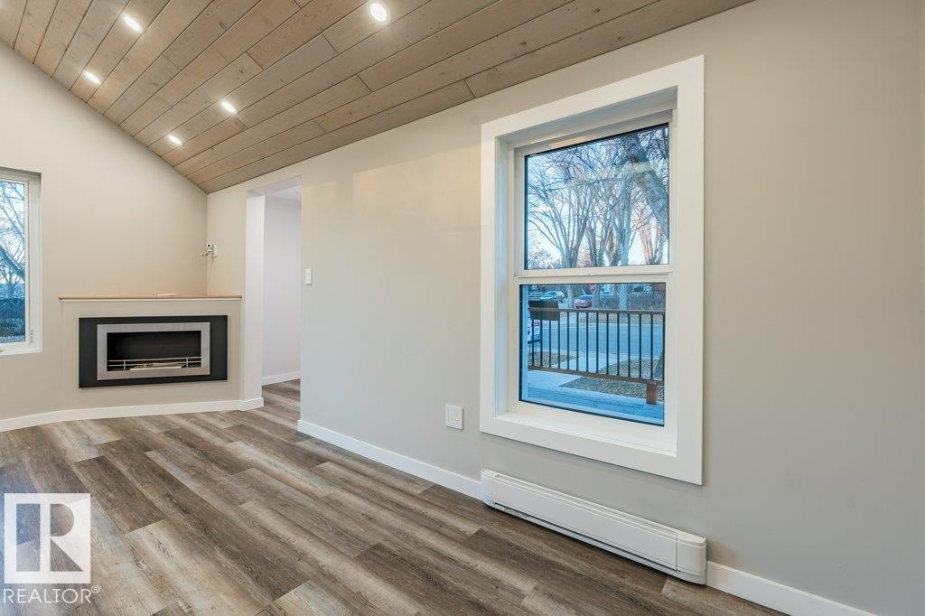 Unfurnished living room with baseboard heating, recessed lighting, a fireplace, a vaulted wooden ceiling, and wood finished floors - 4713 48 Avenue, Wetaskiwin, AB - Indoor With Fireplace