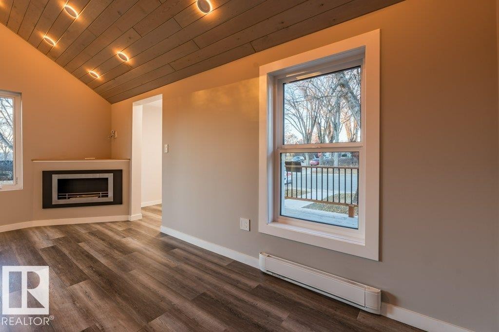Unfurnished living room with a baseboard heating unit, a vaulted wooden ceiling, wood finished floors, a fireplace, and recessed lighting - 4713 48 Avenue, Wetaskiwin, AB - Indoor With Fireplace