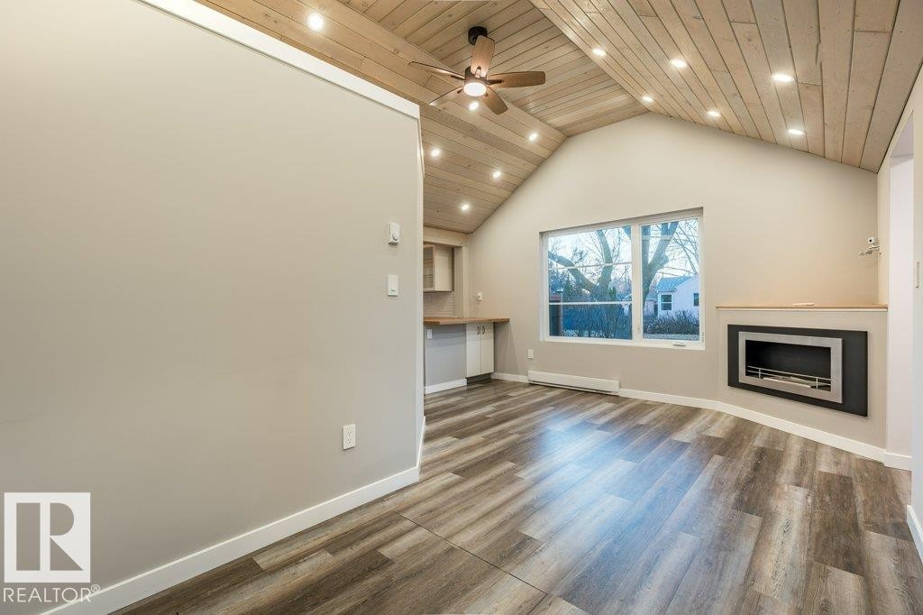 Unfurnished living room featuring a ceiling fan, wood finished floors, a fireplace, recessed lighting, and baseboard heating - 4713 48 Avenue, Wetaskiwin, AB - Indoor With Fireplace