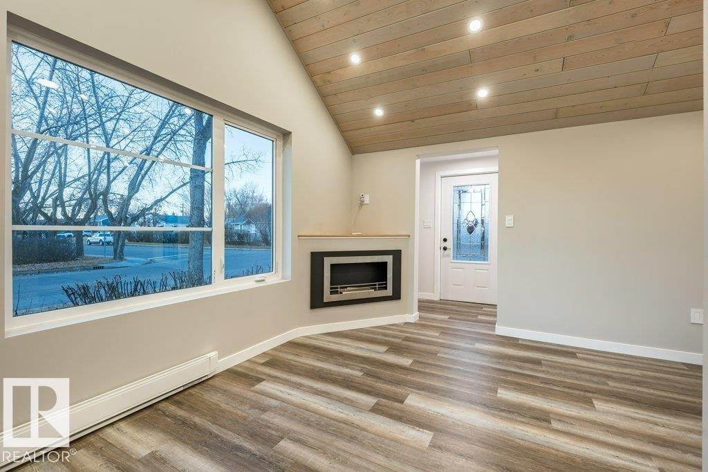 Unfurnished living room featuring a baseboard radiator, wood finished floors, recessed lighting, a vaulted wood ceiling, and a fireplace - 4713 48 Avenue, Wetaskiwin, AB - Indoor With Fireplace