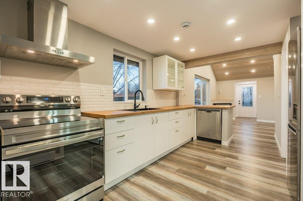 Kitchen featuring stainless steel appliances, glass fronted cabinets, a peninsula, lofted ceiling with beams, and backsplash - 4713 48 Avenue, Wetaskiwin, AB - Indoor Photo Showing Kitchen With Upgraded Kitchen