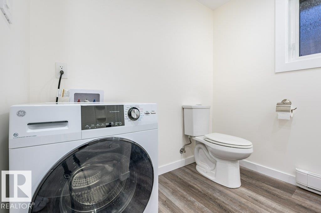 Laundry area featuring washer / clothes dryer, wood finished floors, and a baseboard heating unit - 4713 48 Avenue, Wetaskiwin, AB - Indoor Photo Showing Laundry Room