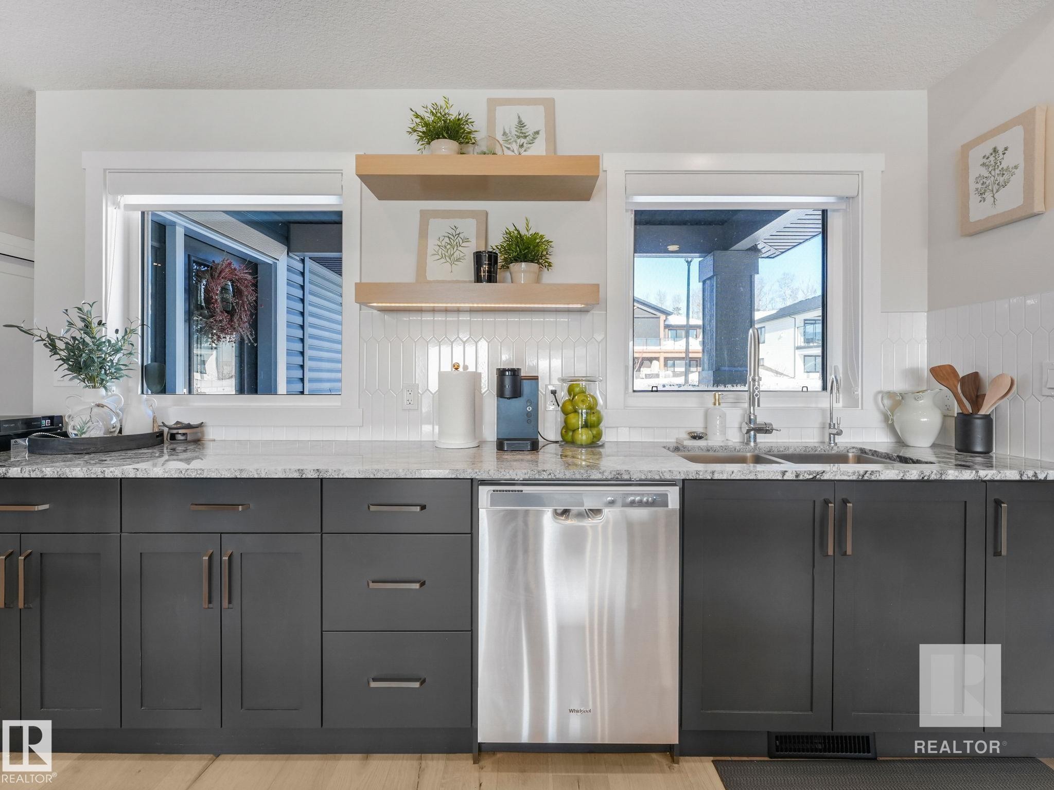 Kitchen with stainless steel dishwasher, light stone countertops, open shelves, light wood finished floors, and a textured ceiling - 209 55101 Ste. Anne Trail, Rural Lac Ste. Anne County, AB - Indoor Photo Showing Kitchen With Upgraded Kitchen