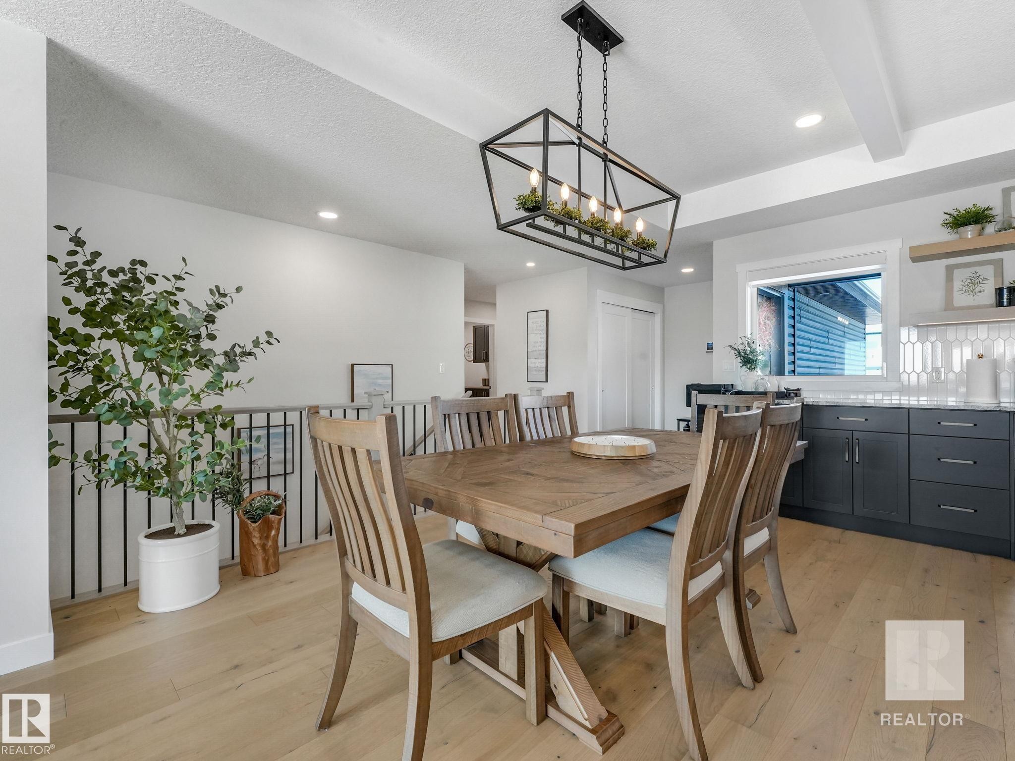 Dining space with light wood finished floors, a textured ceiling, a chandelier, and beam ceiling - 209 55101 Ste. Anne Trail, Rural Lac Ste. Anne County, AB - Indoor Photo Showing Dining Room