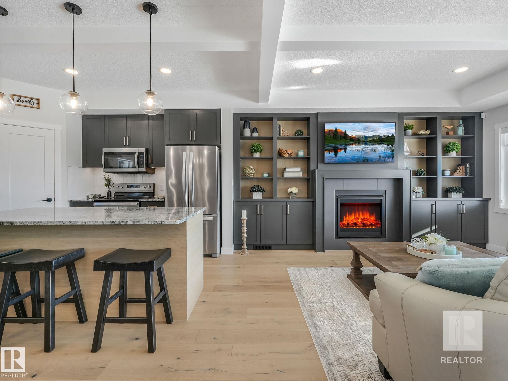Living area with a textured ceiling, light wood-style flooring, recessed lighting, a tiled fireplace, and beam ceiling - 209 55101 Ste. Anne Trail, Rural Lac Ste. Anne County, AB - Indoor With Fireplace