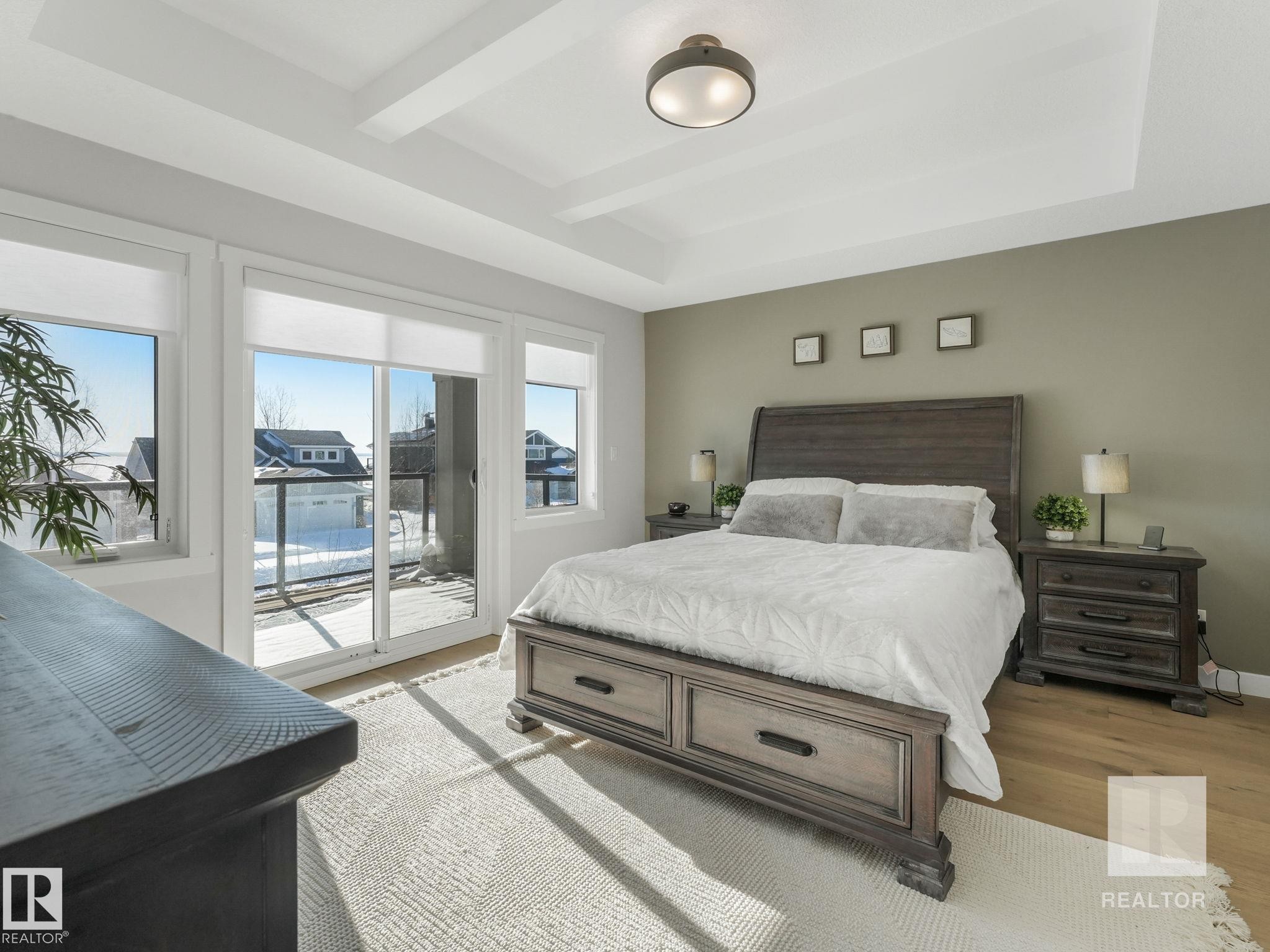 Bedroom featuring a tray ceiling, access to outside, and wood finished floors - 209 55101 Ste. Anne Trail, Rural Lac Ste. Anne County, AB - Indoor Photo Showing Bedroom
