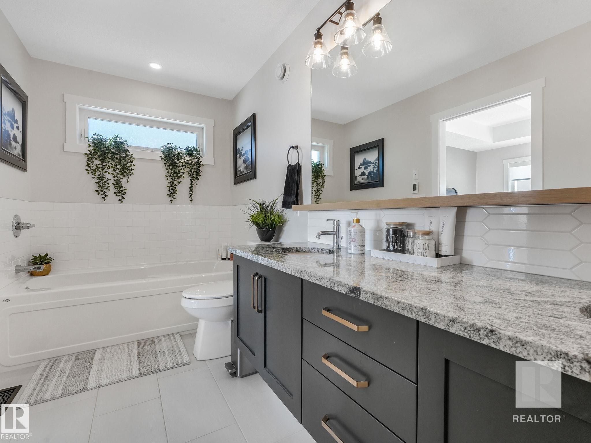 Bathroom featuring vanity, a bath, light tile patterned floors, and backsplash - 209 55101 Ste. Anne Trail, Rural Lac Ste. Anne County, AB - Indoor Photo Showing Bathroom
