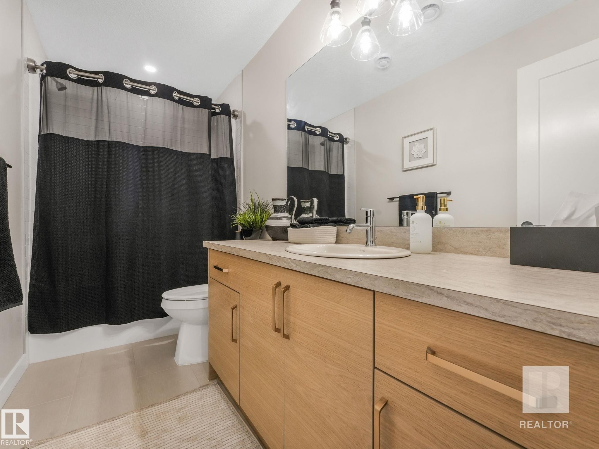 Full bath featuring vanity, light tile patterned flooring, and shower / tub combo with curtain - 209 55101 Ste. Anne Trail, Rural Lac Ste. Anne County, AB - Indoor Photo Showing Bathroom