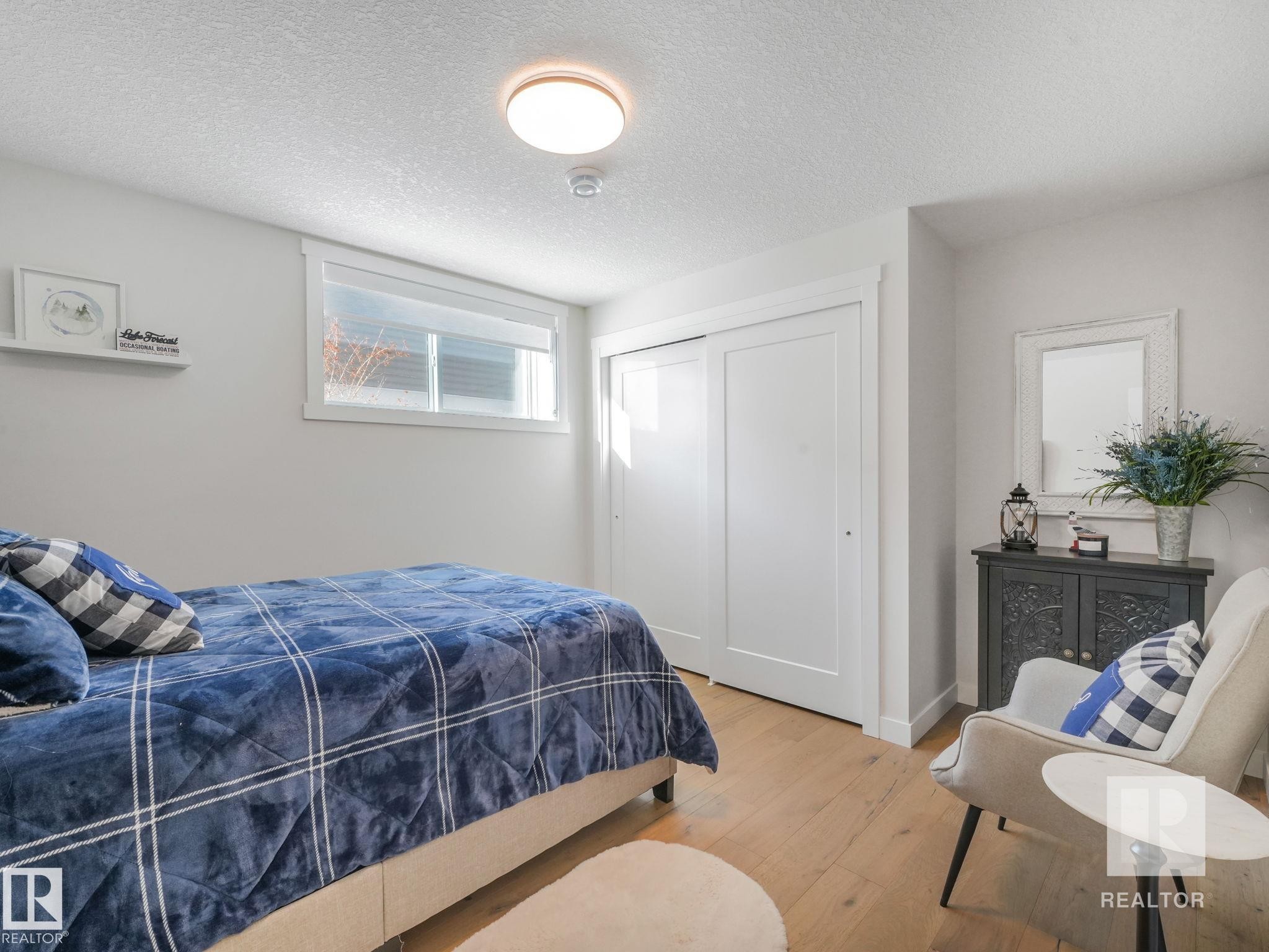 Bedroom featuring wood-type flooring, a textured ceiling, and a closet - 209 55101 Ste. Anne Trail, Rural Lac Ste. Anne County, AB - Indoor Photo Showing Bedroom