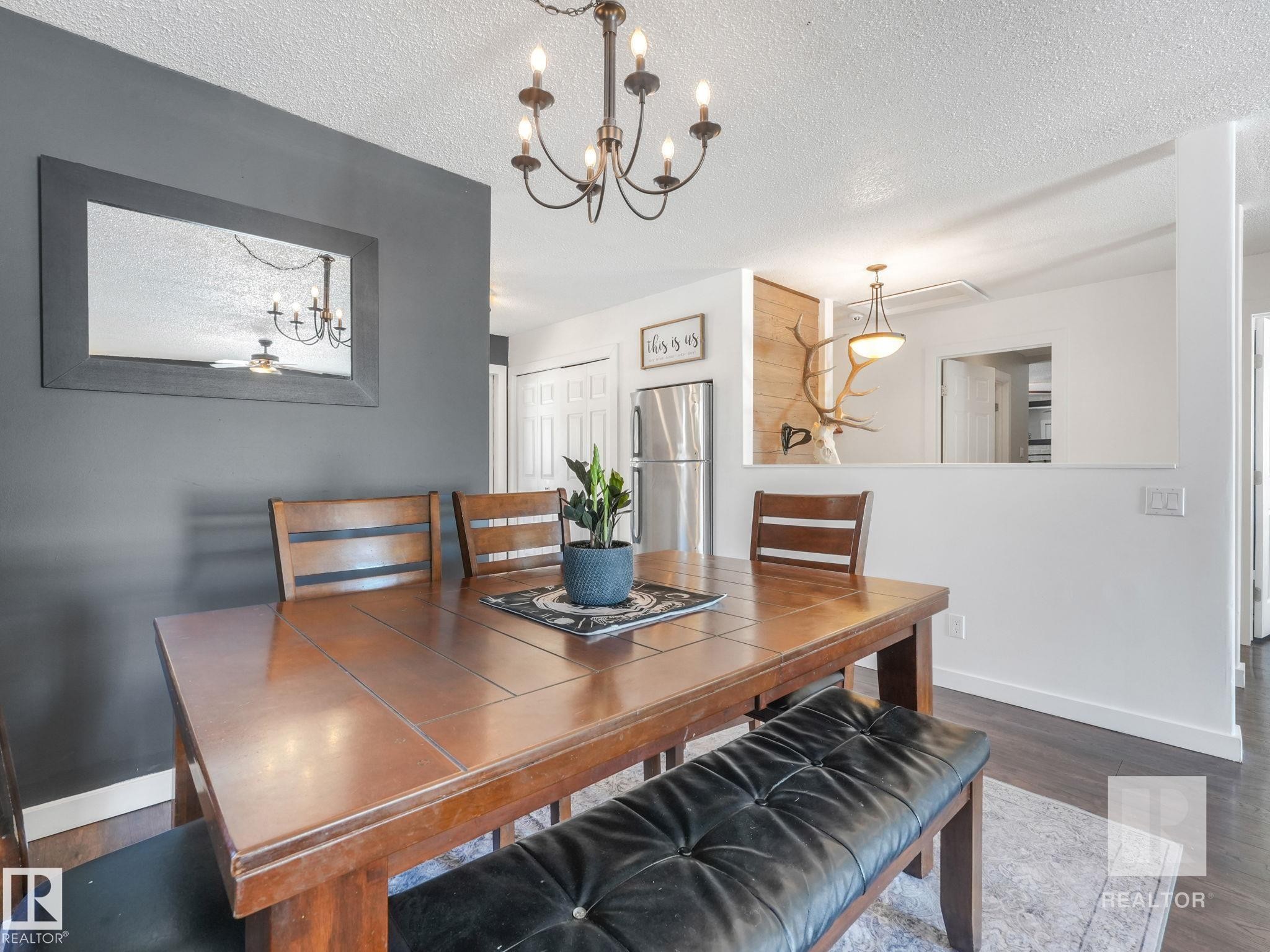 Dining area featuring dark wood-type flooring, suspended lighting, and a textured ceiling - 4504 48 Avenue, Onoway, AB - Indoor Photo Showing Dining Room