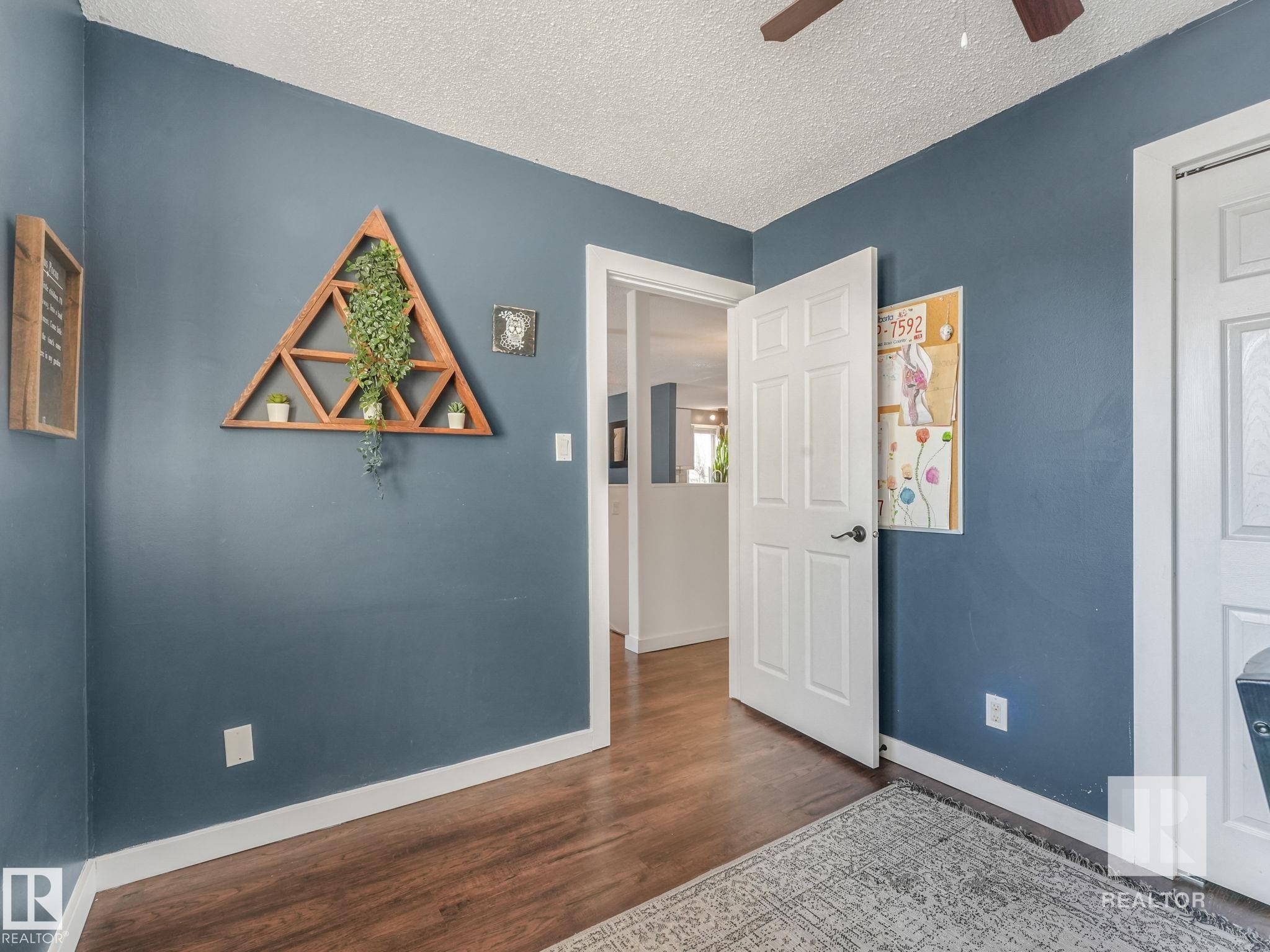 Bedroom featuring dark wood-style flooring, ceiling fan, and a textured ceiling - 4504 48 Avenue, Onoway, AB - Indoor Photo Showing Other Room