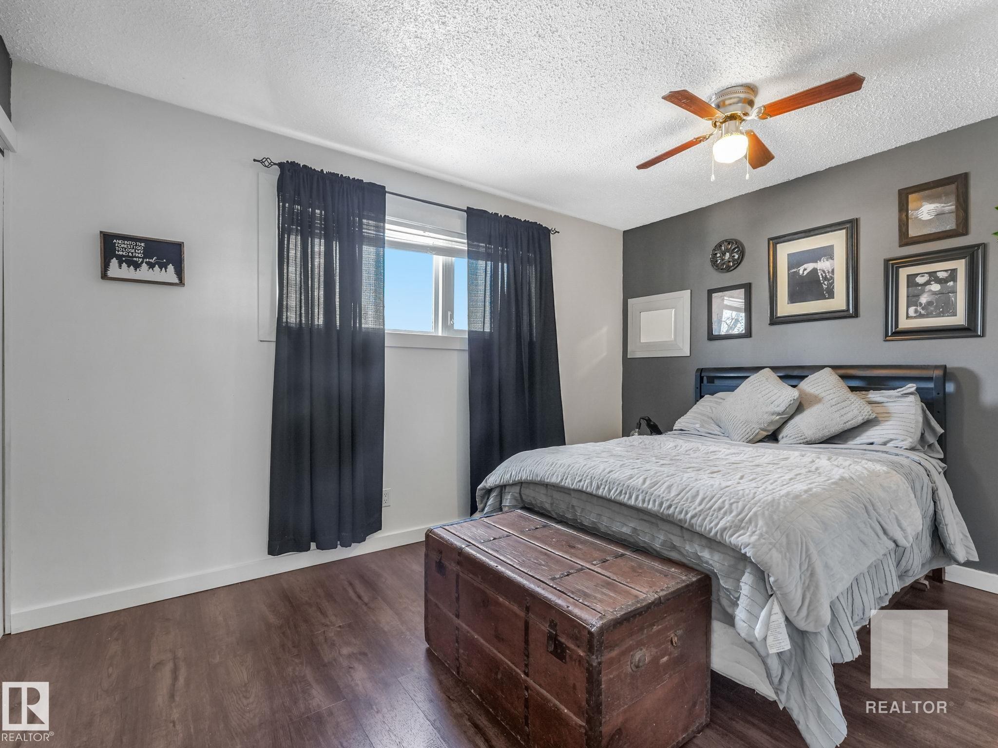Bedroom featuring dark wood-style flooring, a ceiling fan, and a textured ceiling - 4504 48 Avenue, Onoway, AB - Indoor Photo Showing Bedroom